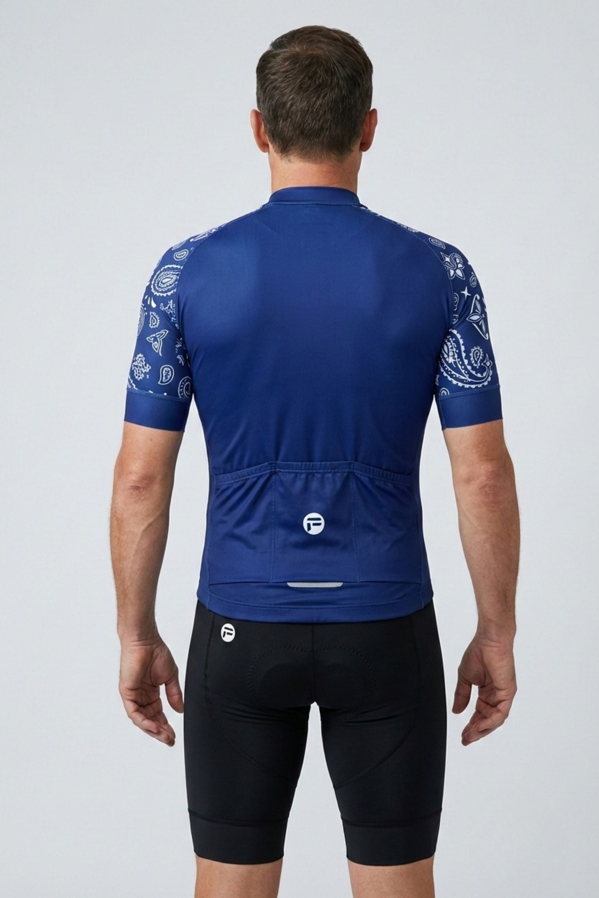 Person wearing a blue cycling jersey with white patterns on sleeves and back, on a light gray background