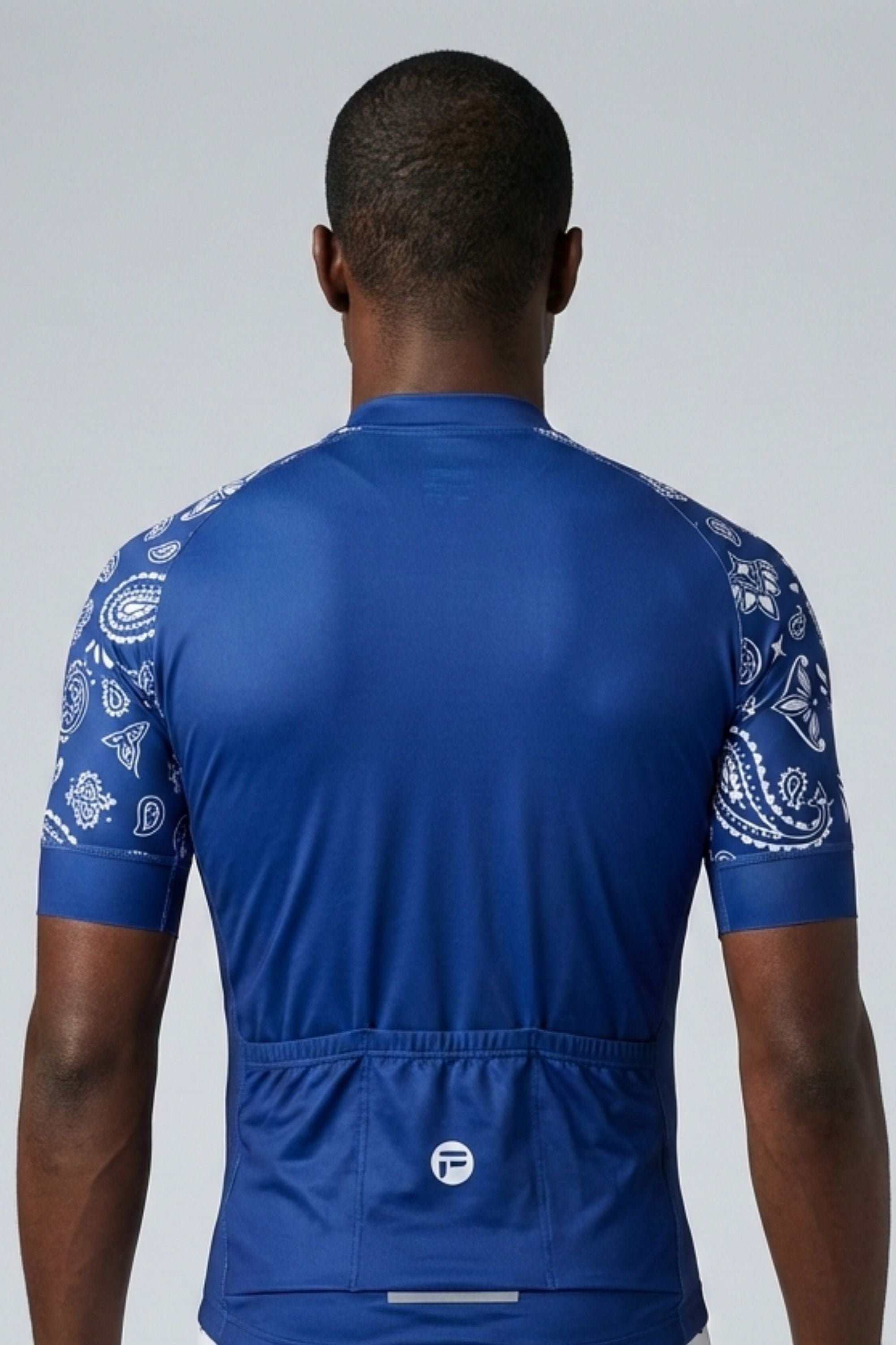 Person wearing a blue cycling jersey with white patterns on sleeves against a gray background