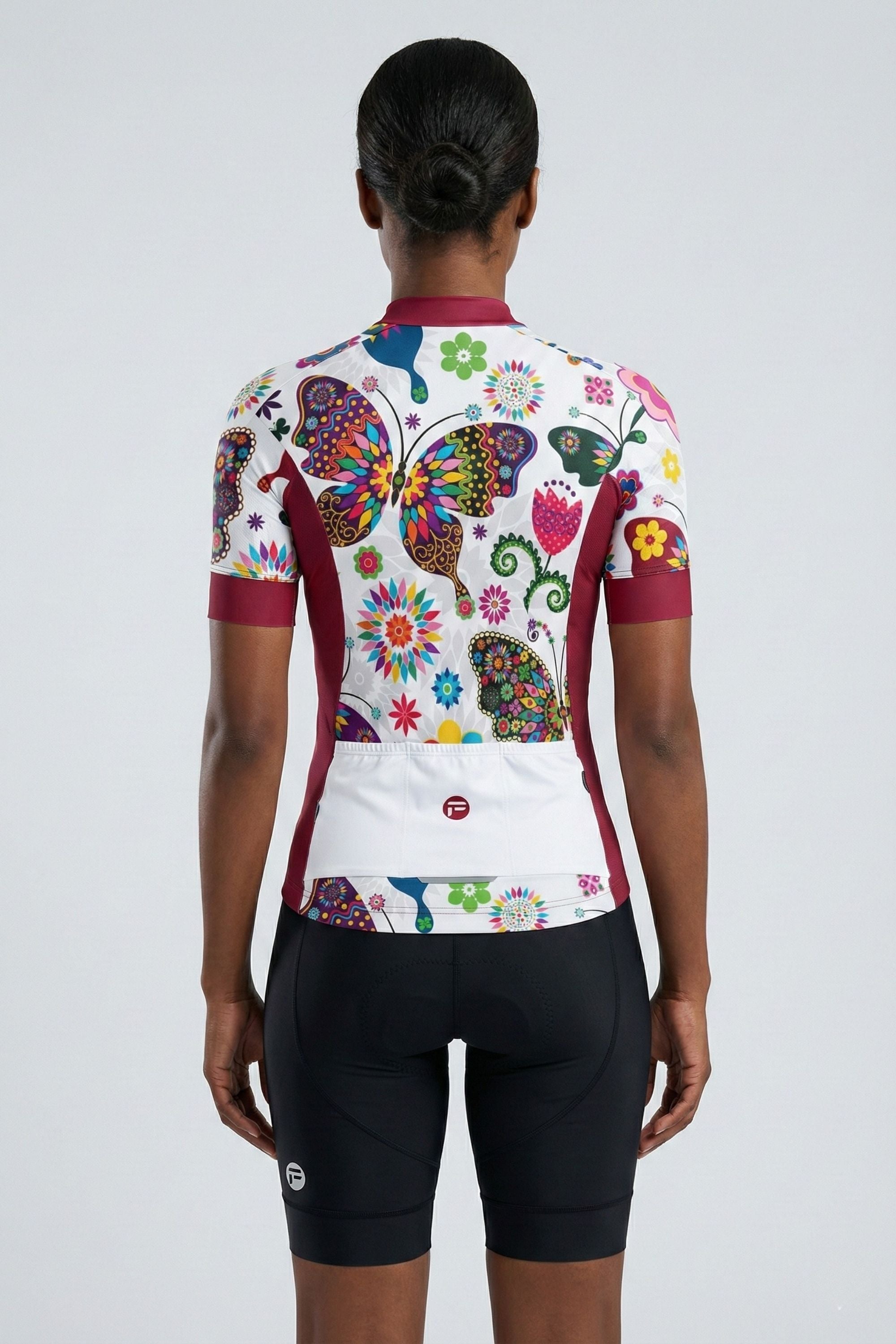 Person wearing a black a cycling outfit with butterflies on a plain background by Cycling Frelsi