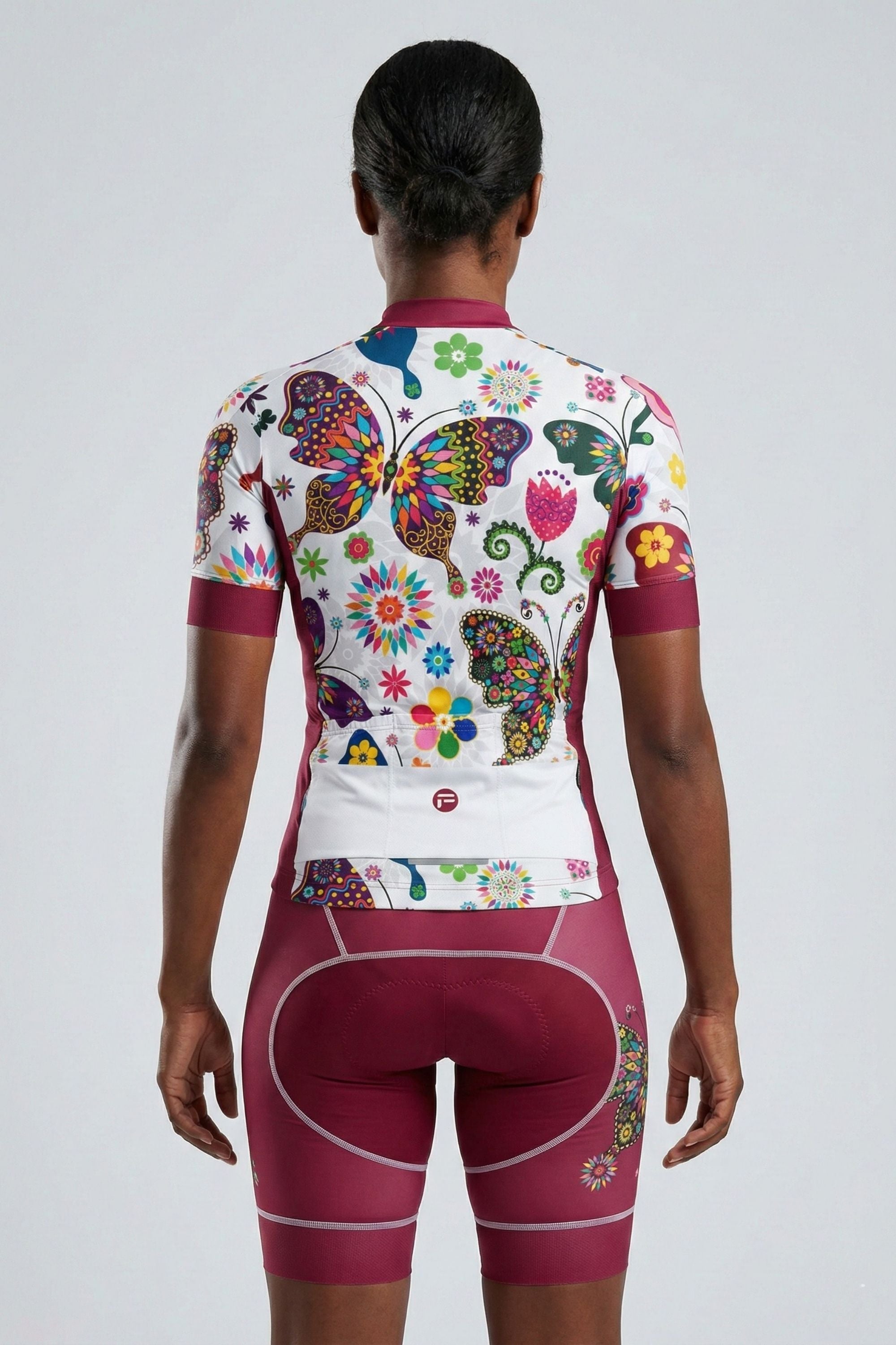 Person wearing a black a cycling outfit with butterflies on a plain background by Cycling Frelsi