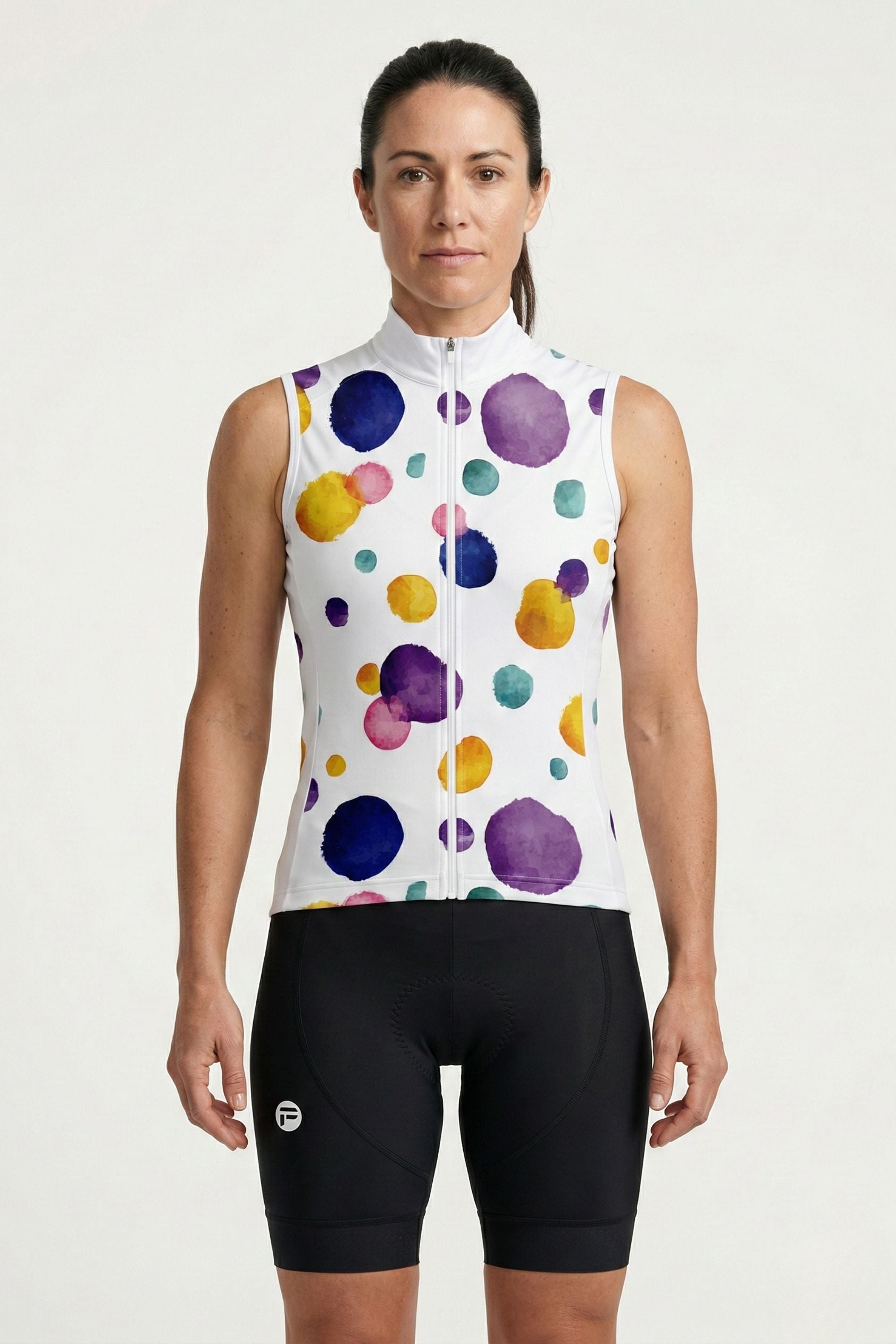 Woman wearing a colorful polka dot cycling jersey and black shorts on a white background