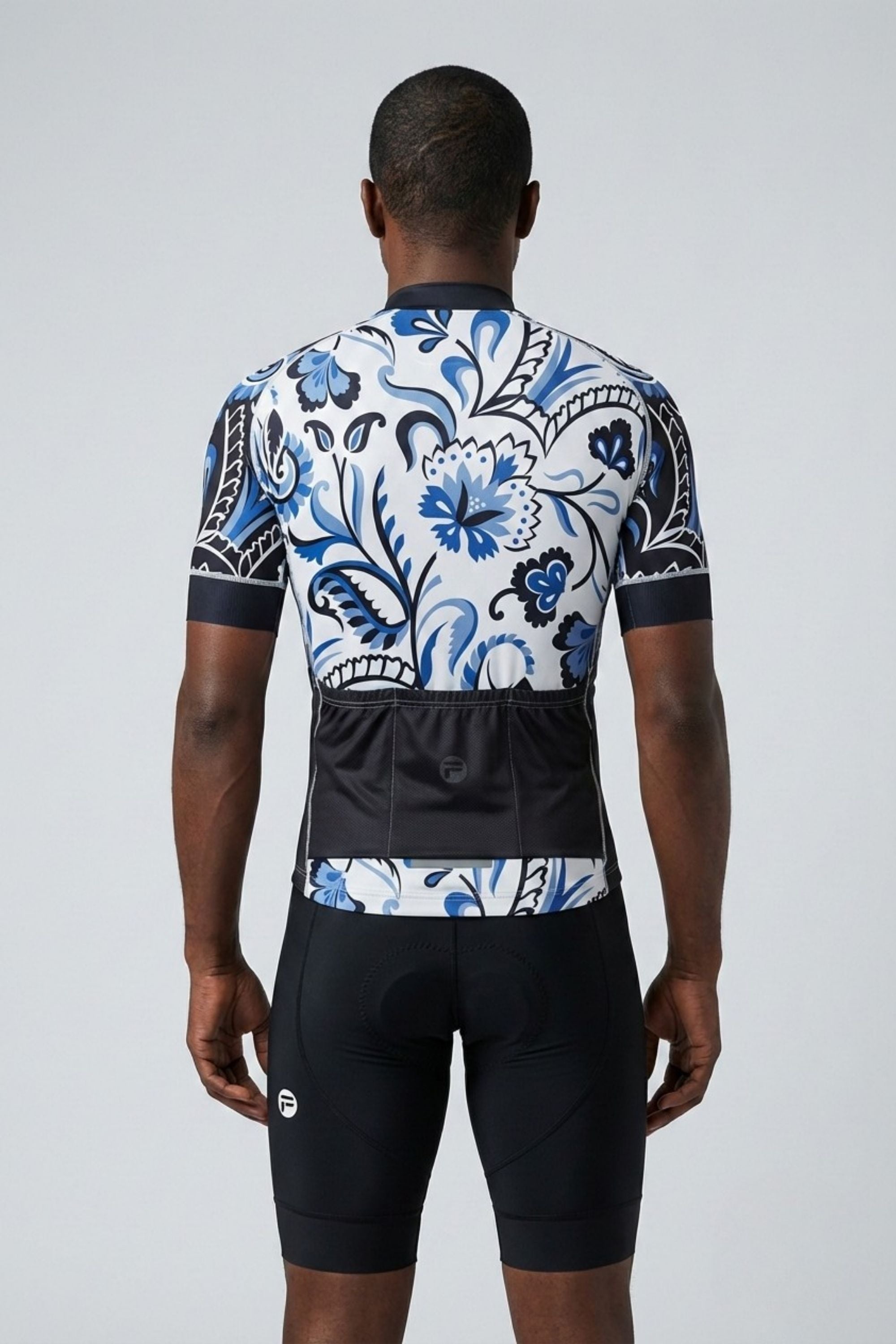Person wearing a blue and white floral cycling jersey and black shorts on a gray background