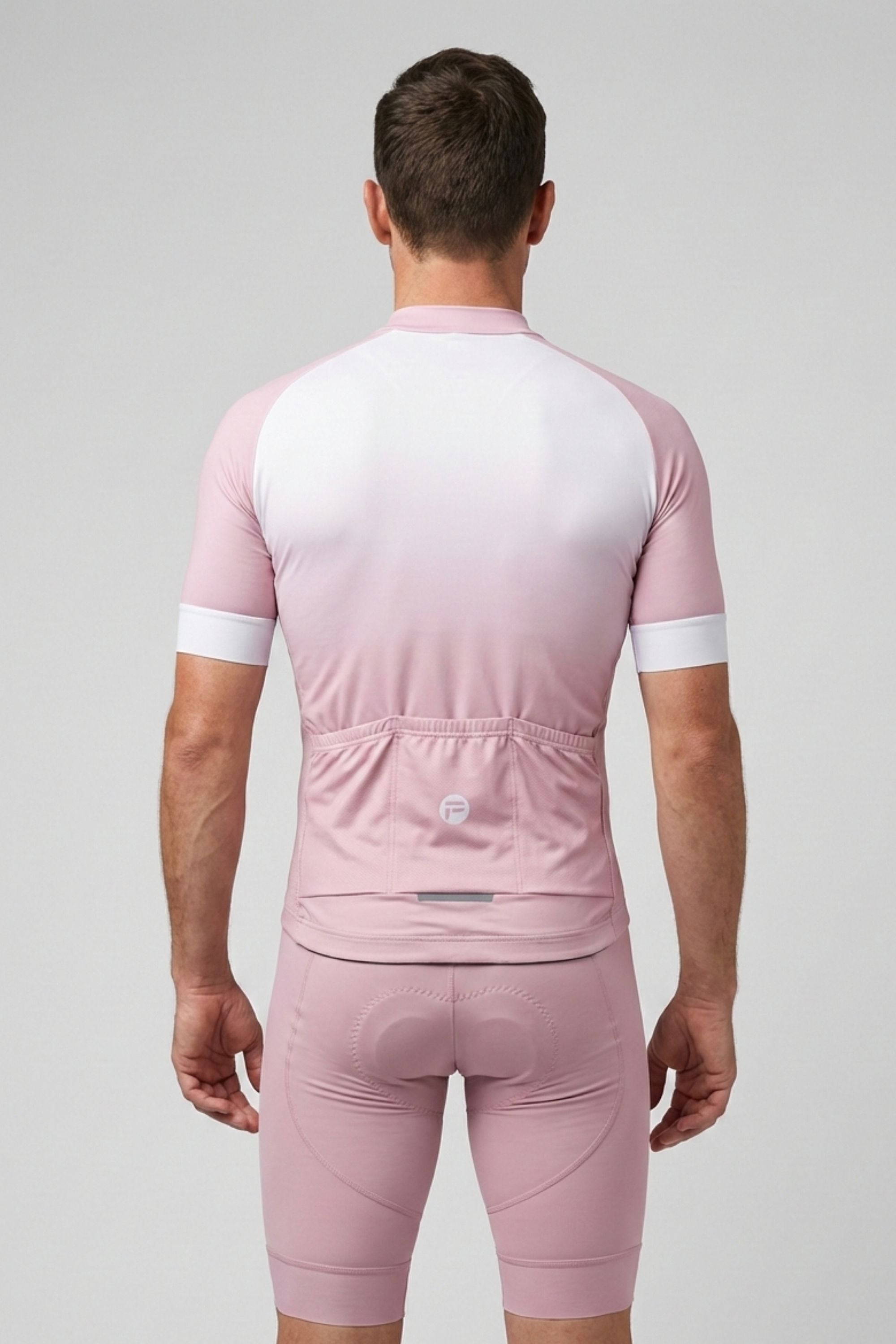Person wearing a pink cycling outfit with white accents on a gray background