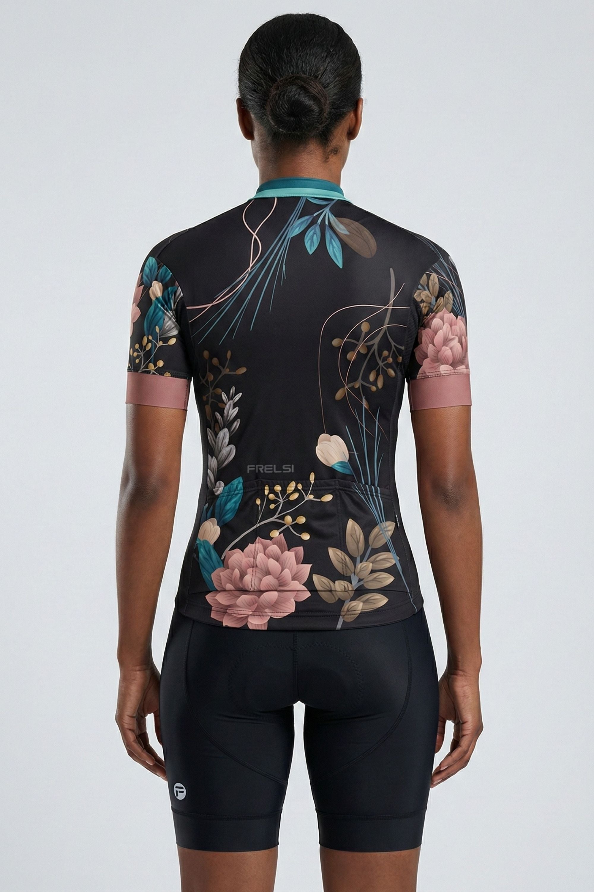 Person wearing a black a cycling outfit with flowers on a plain background by Cycling Frelsi