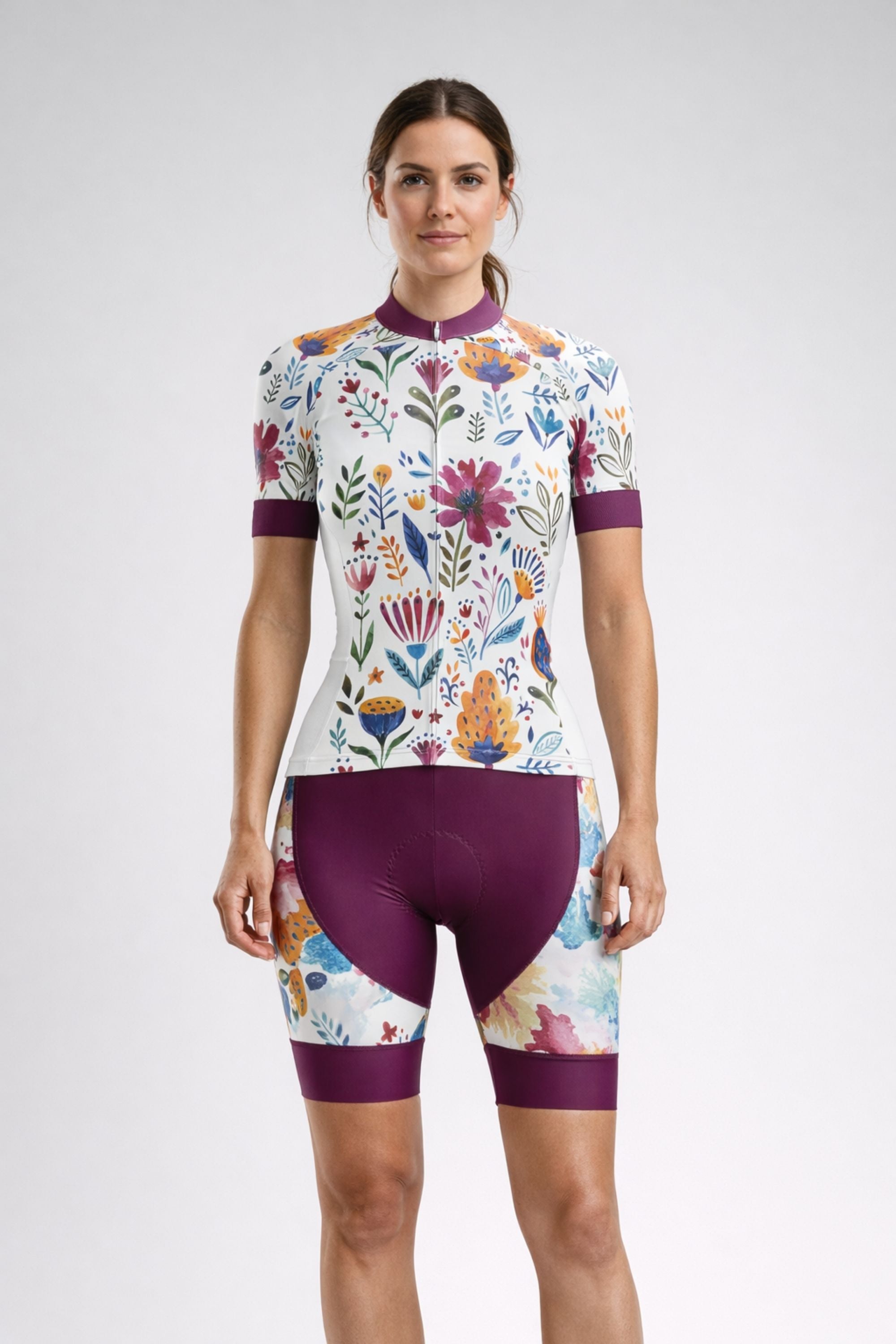 Woman wearing a colorful floral cycling outfit on a white background - Garden Art | Women's Short Sleeve Cycling Set by Cycling Frelsi