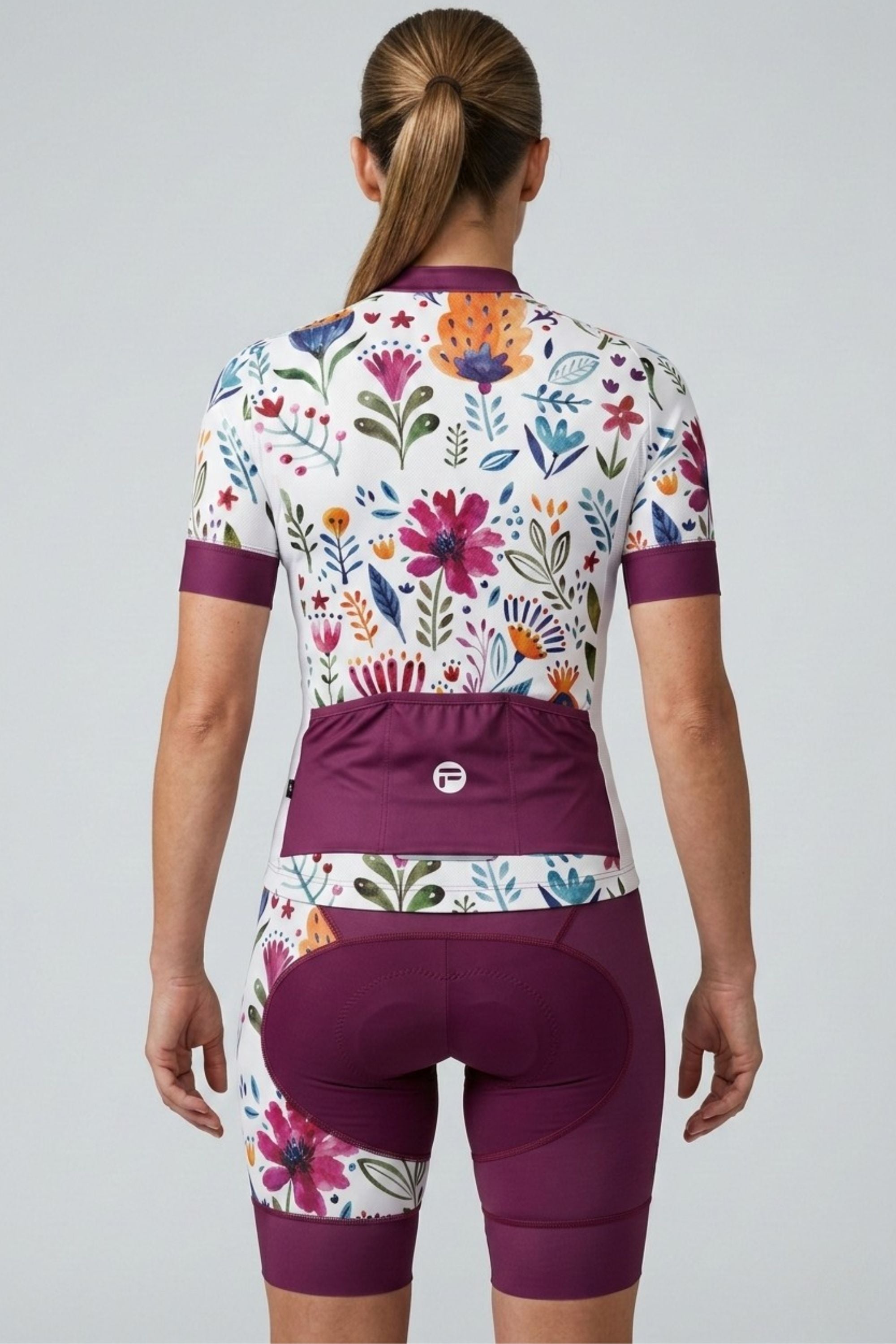 Person wearing a floral cycling jersey and shorts on a plain background