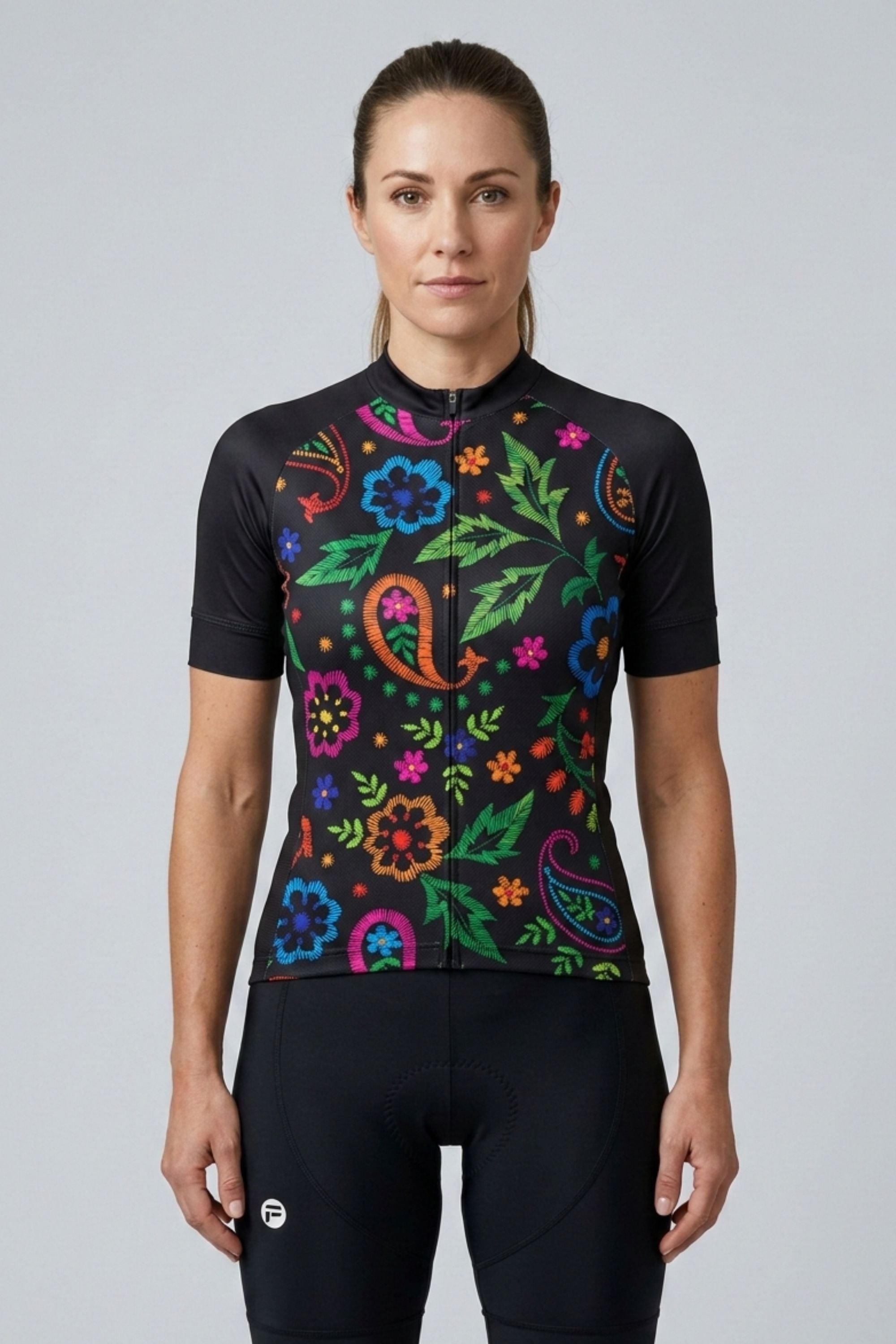 Woman wearing a black cycling jersey with colorful floral patterns on a gray background