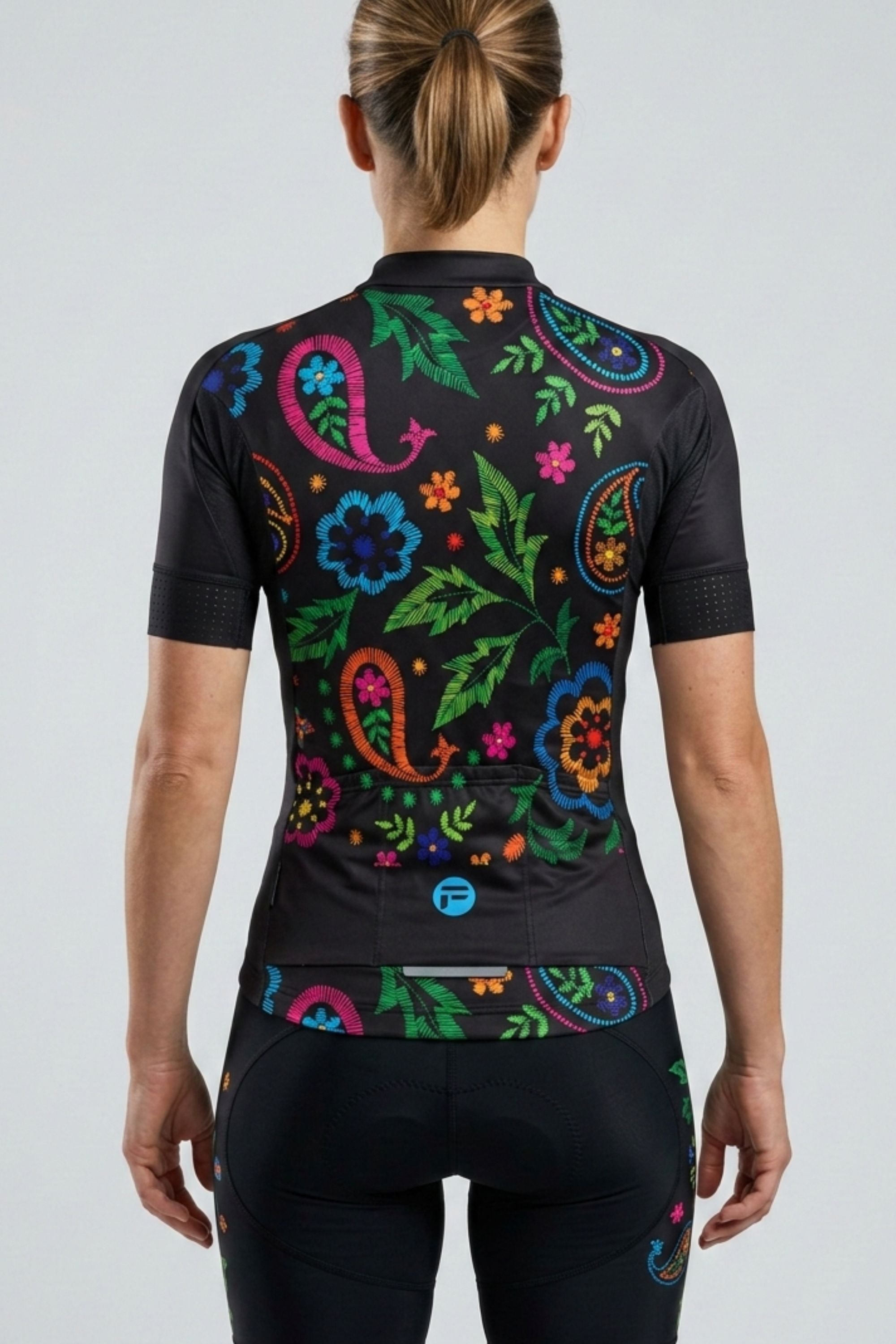 Person wearing a black cycling jersey with colorful floral patterns on a white background