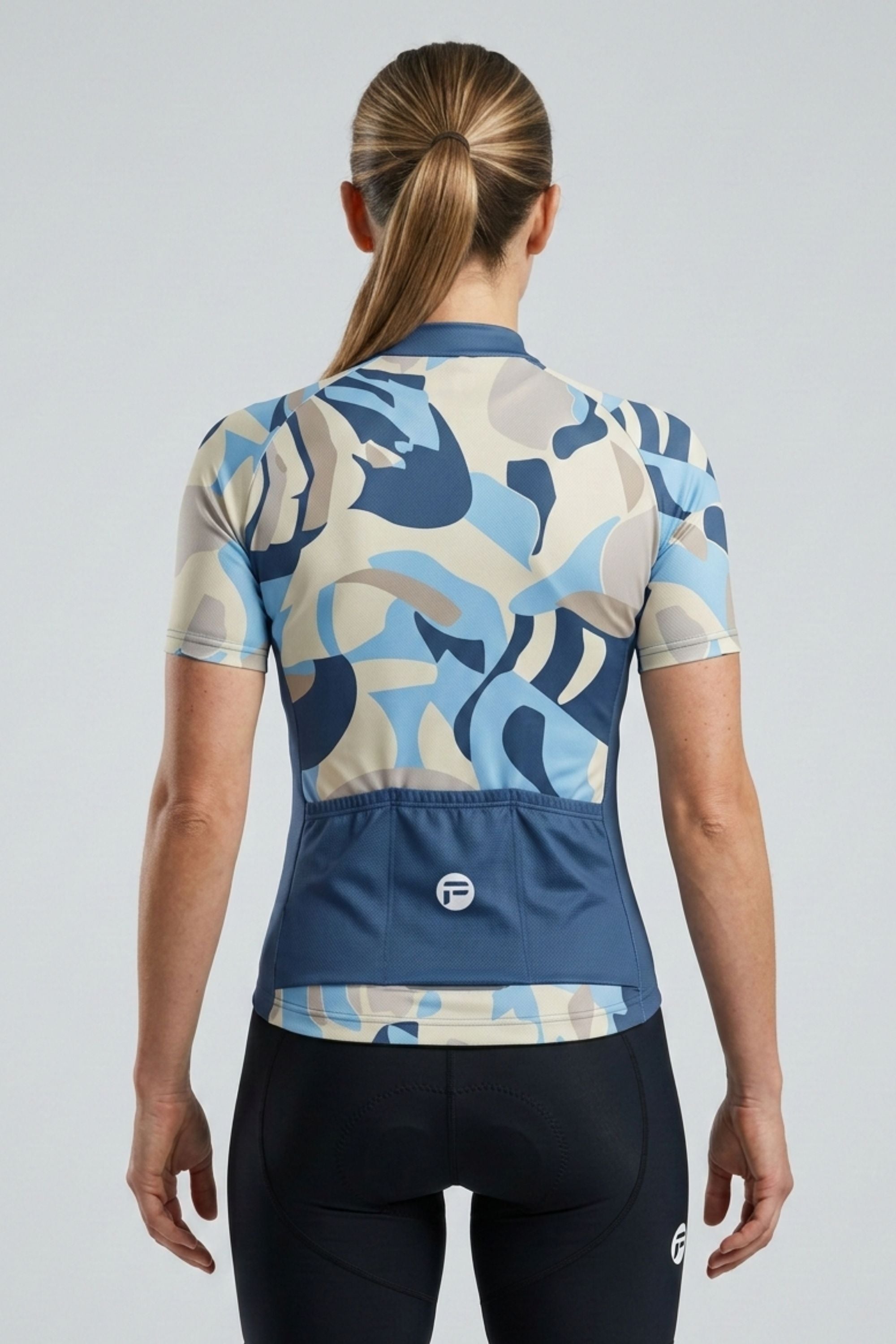 Person wearing a blue and beige camouflage cycling jersey on a light gray background