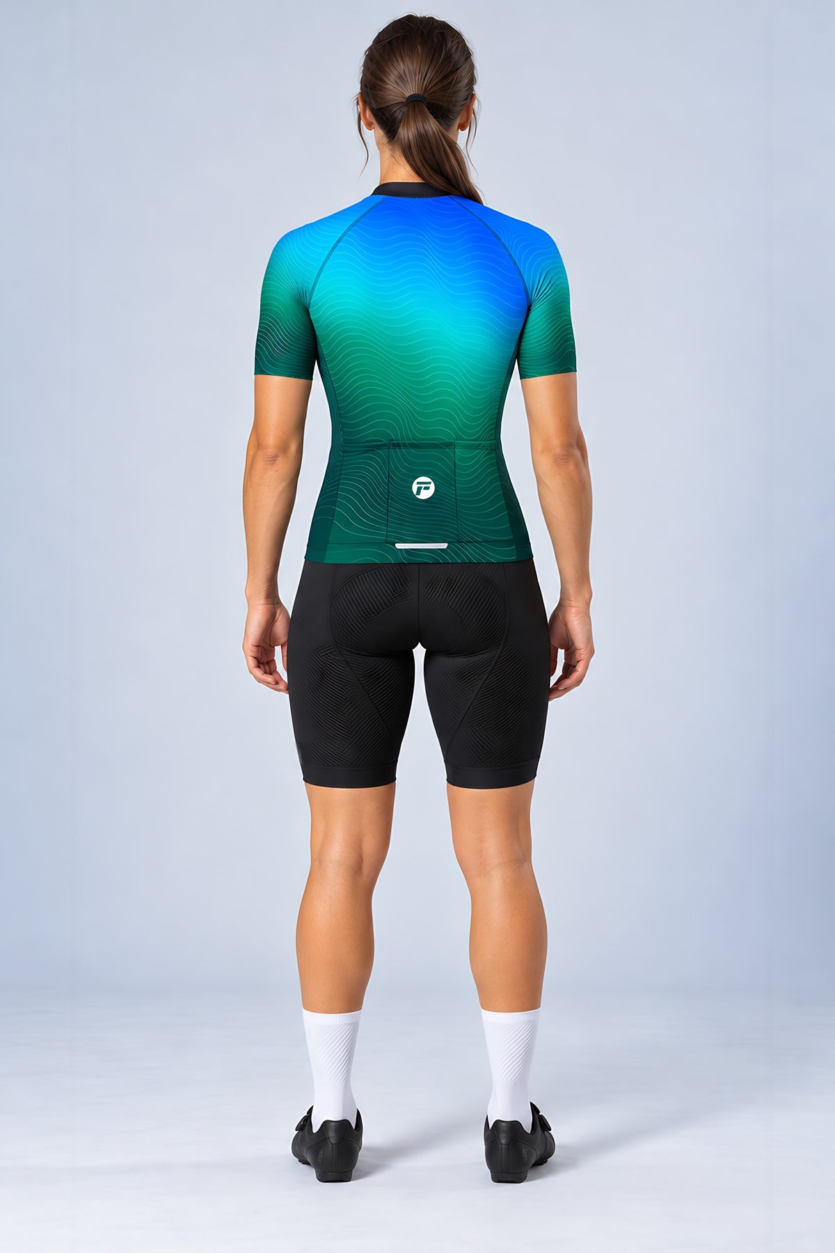 Woman wearing the Ocean Pulse short sleeve cycling jersey with black bib shorts - back view