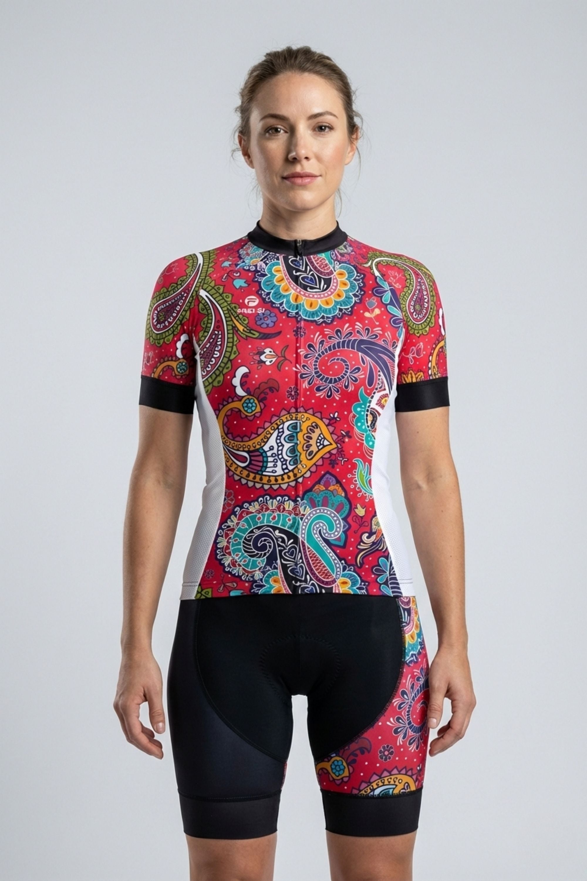 Woman wearing a colorful cycling outfit by Cycling Frelsi with a patterned jersey and black shorts on a light gray background