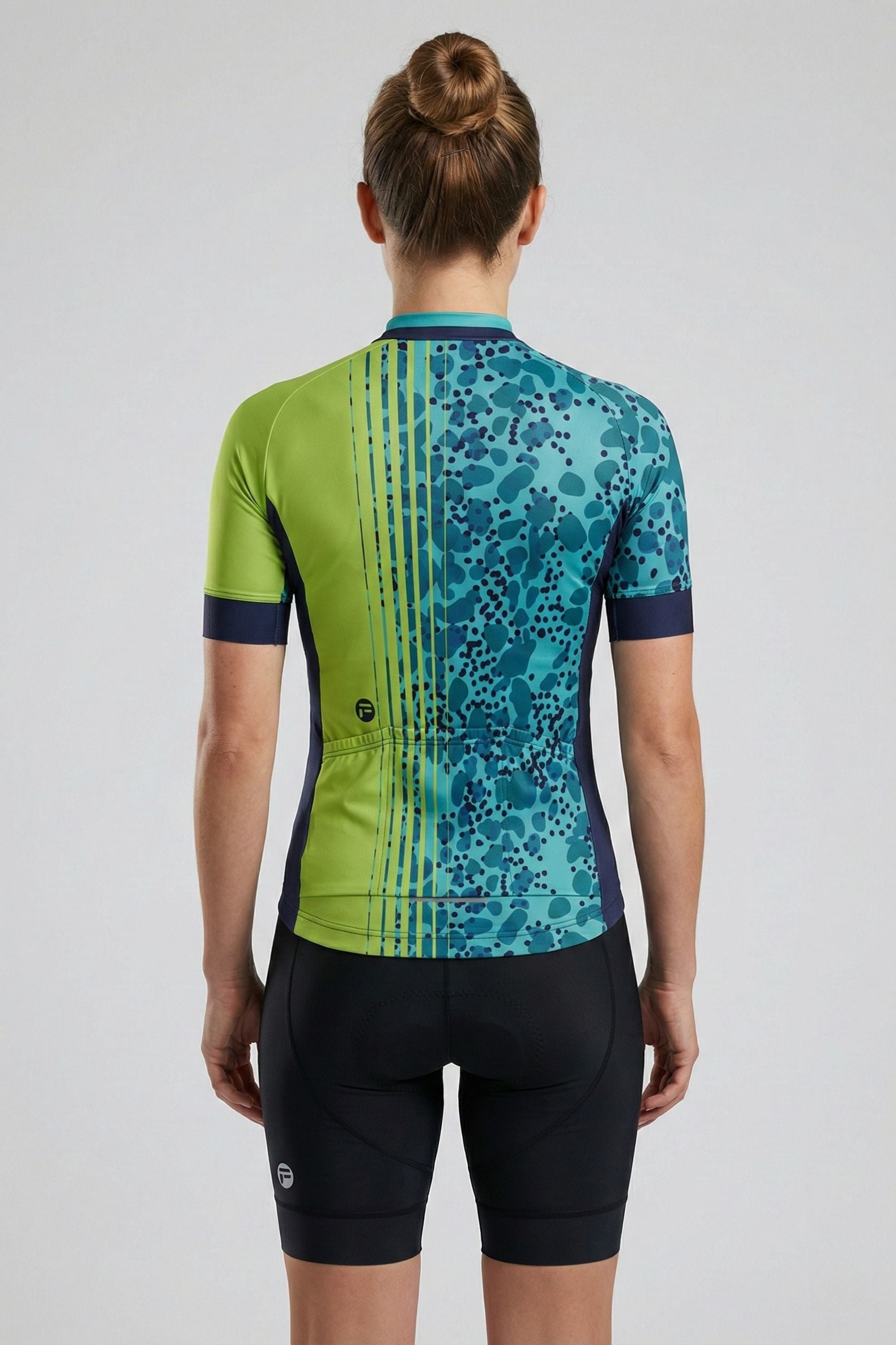 Person wearing a green and blue cycling outfit on a plain background by Cycling Frelsi