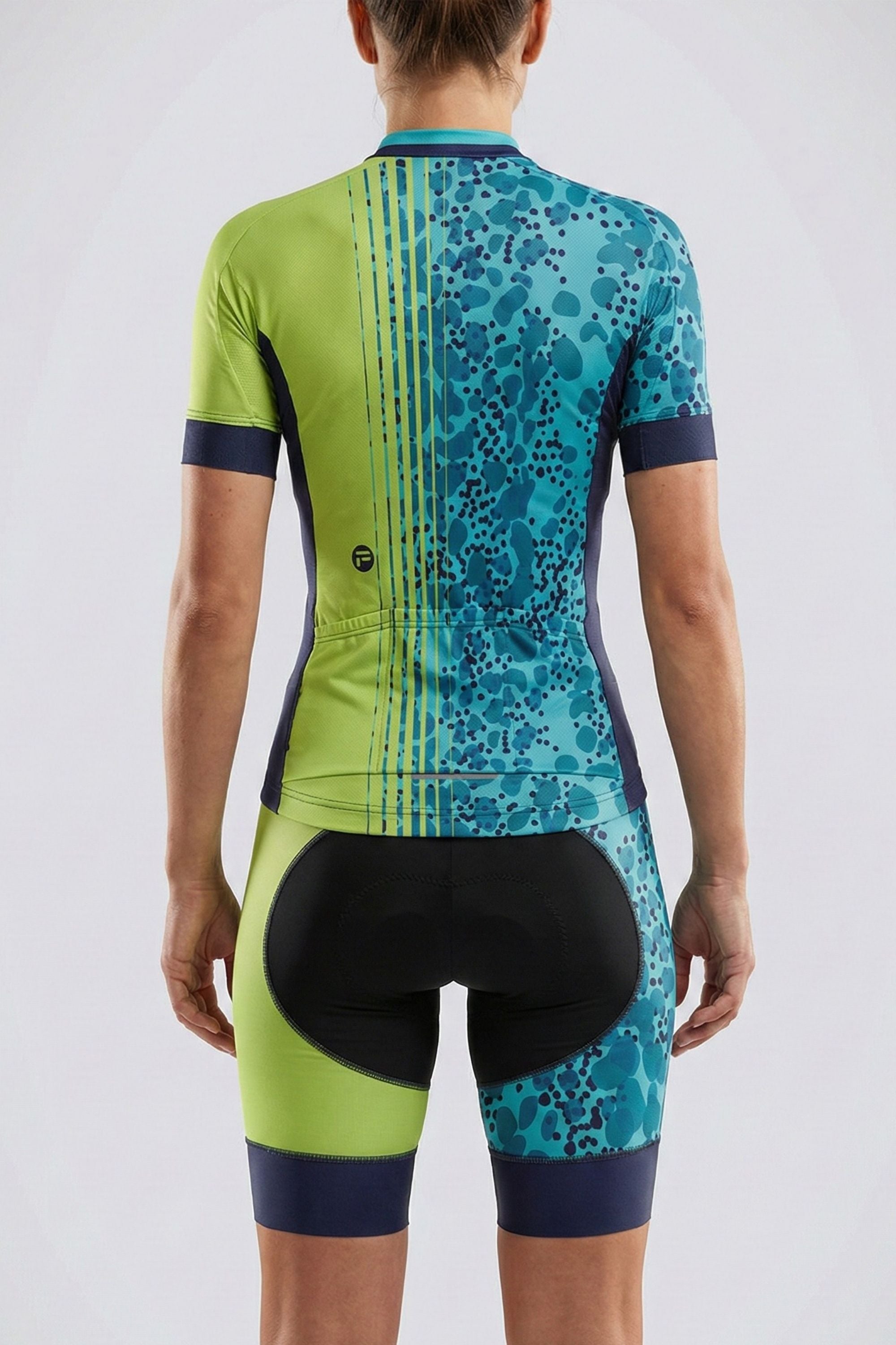 Person wearing a green and blue cycling outfit on a plain background by Cycling Frelsi