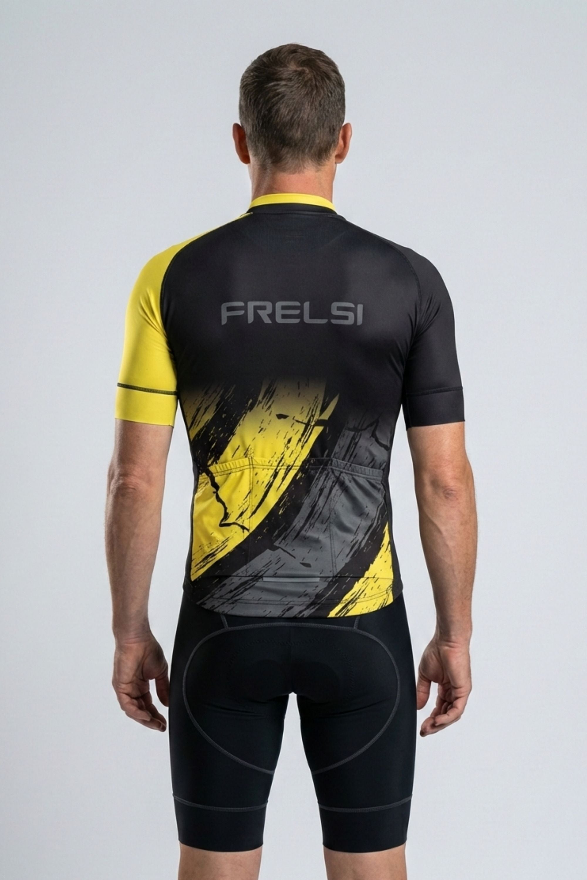 Person wearing a black and yellow cycling outfit with 'FRELSI' branding on a gray background