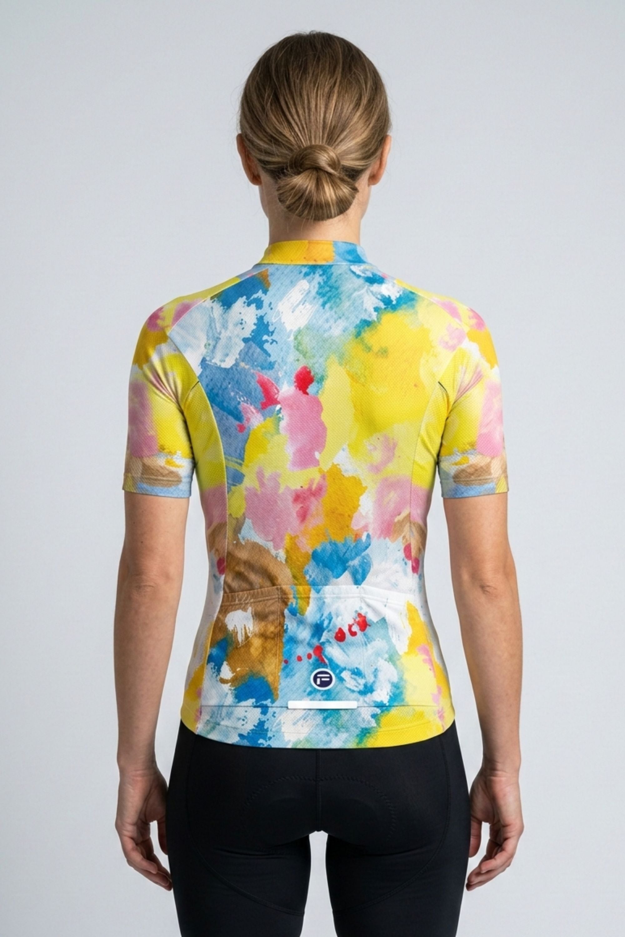 Person wearing a colorful cycling jersey with abstract design on a plain background