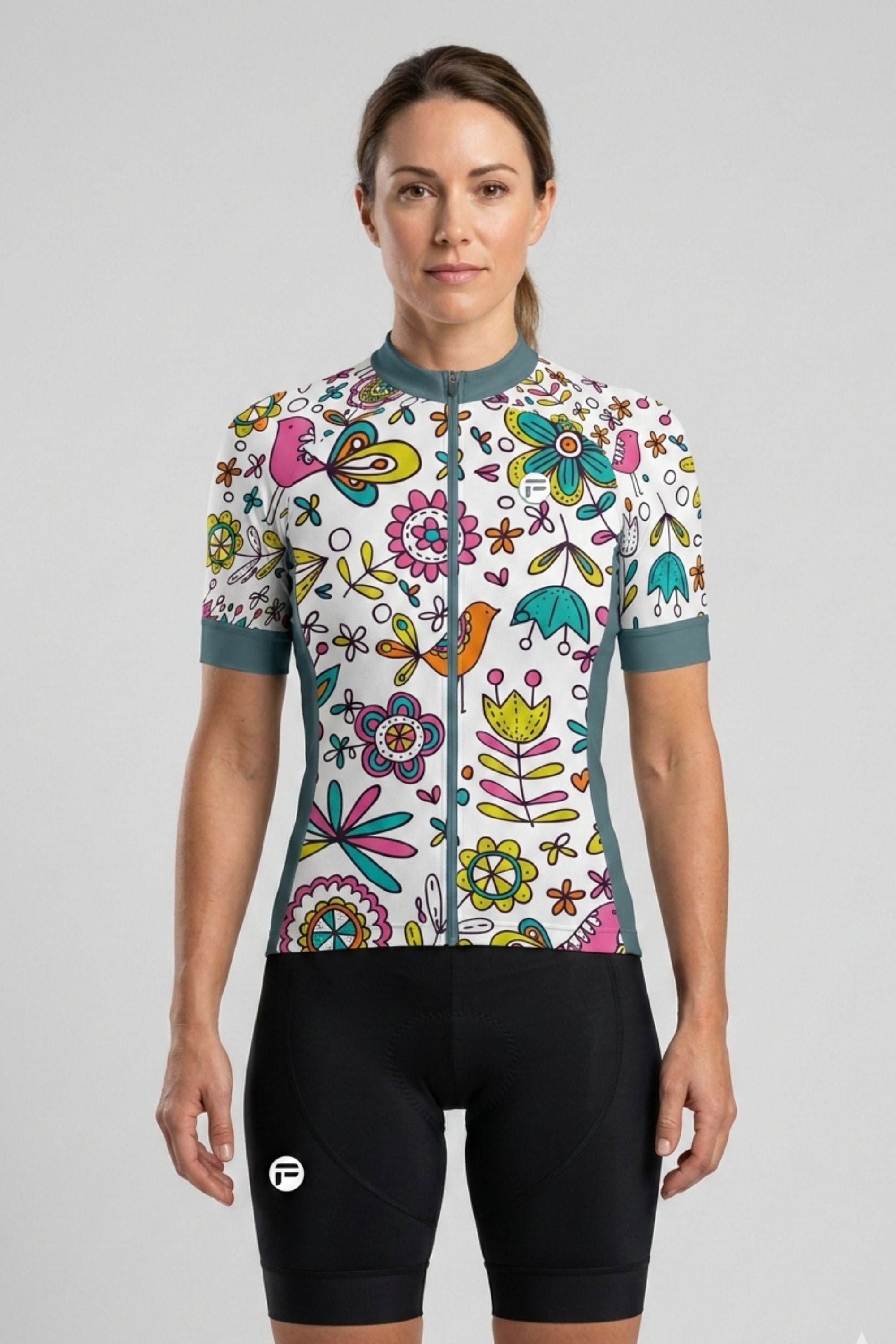 Woman wearing a colorful floral cycling jersey and black shorts on a gray background