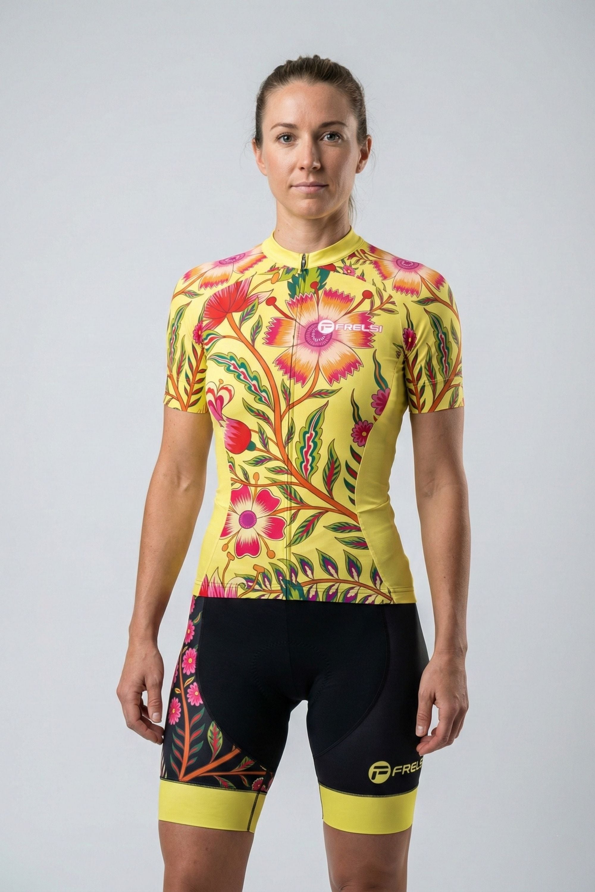 Person wearing a yellow cycling outfit with pink flowers on a plain background by Cycling Frelsi