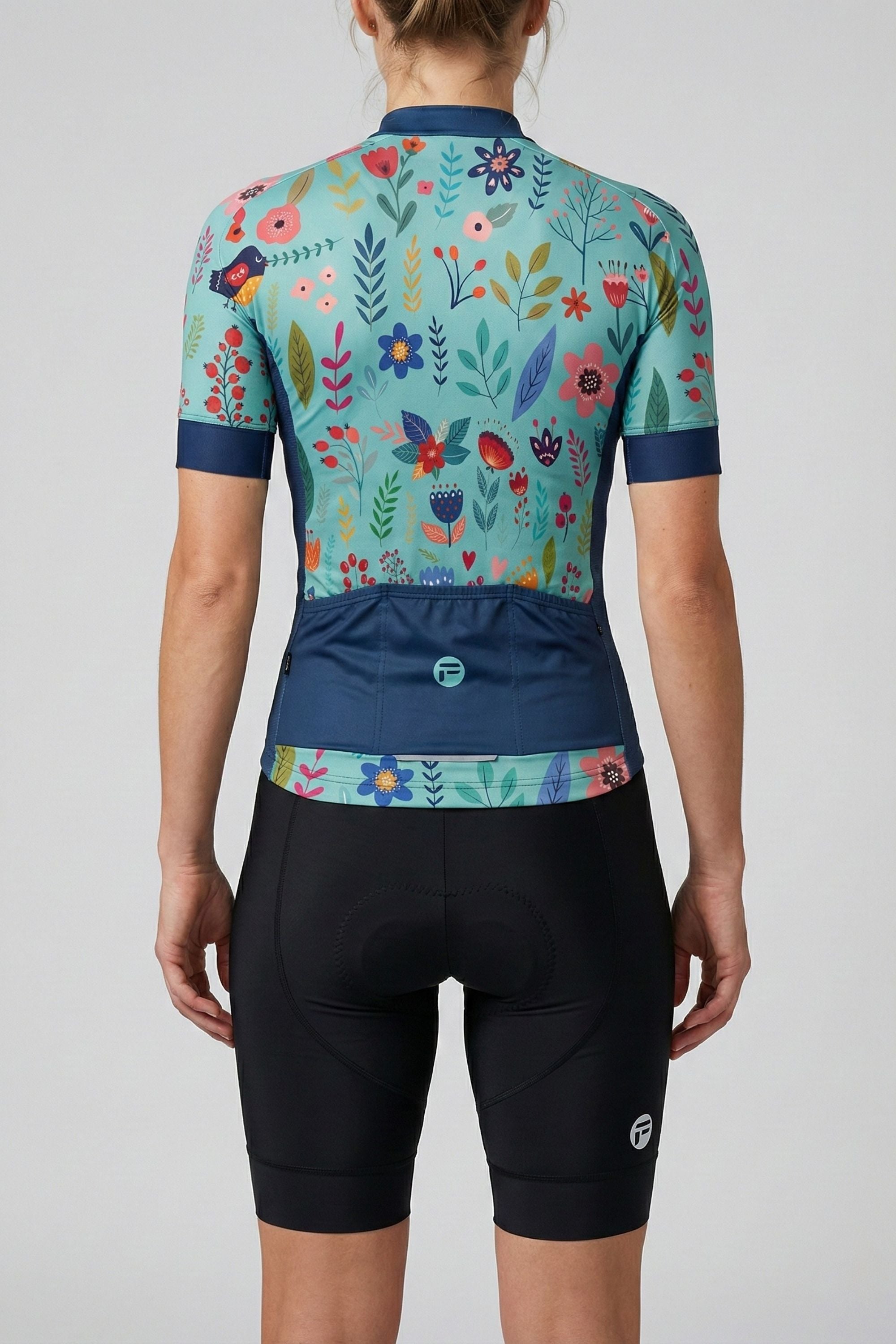 Person wearing a blue cycling jersey with colorful flowers accents by Cycling Frelsi on a gray background
