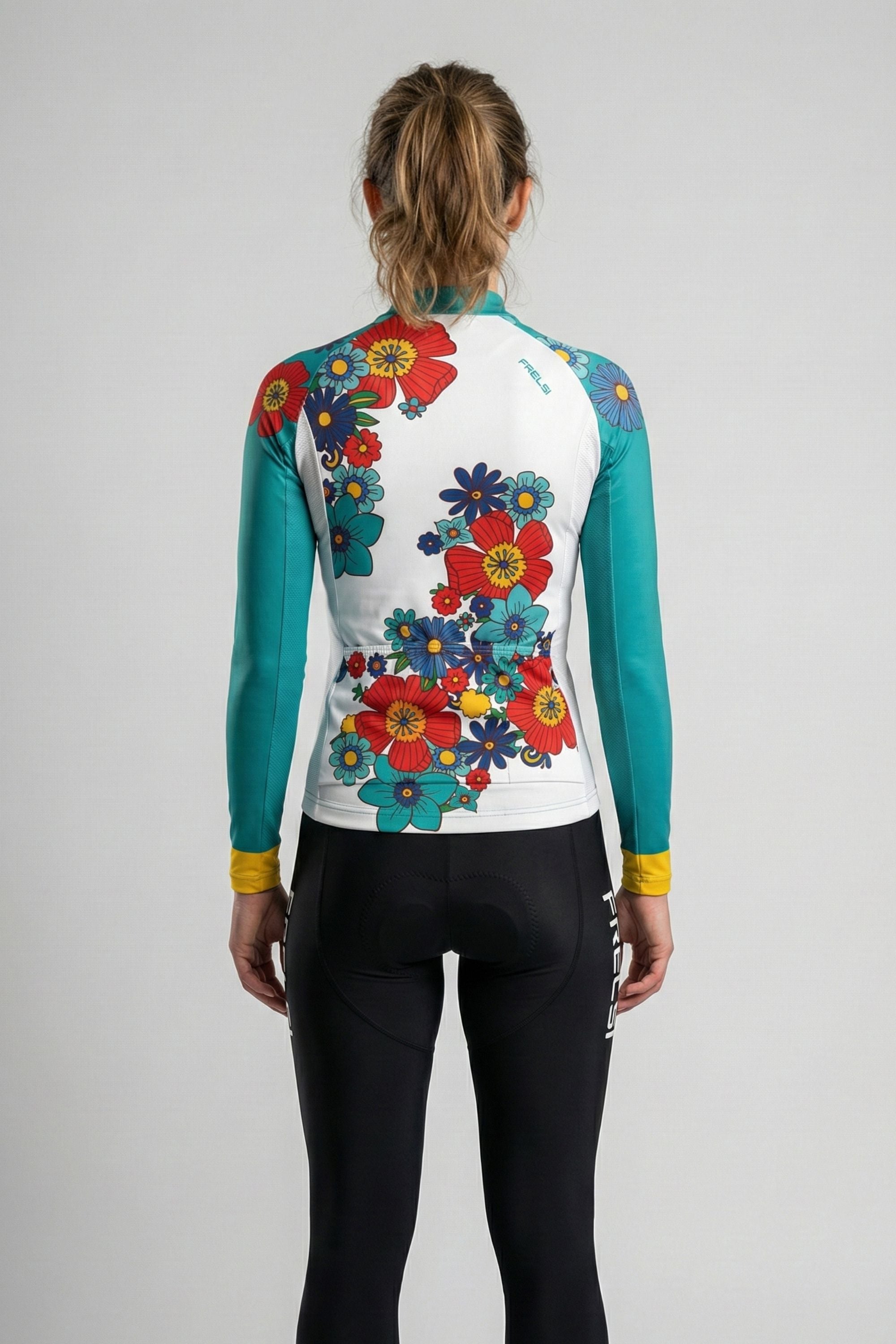 Person wearing a cycling jersey with colorful flowers accents by Cycling Frelsi on a gray background