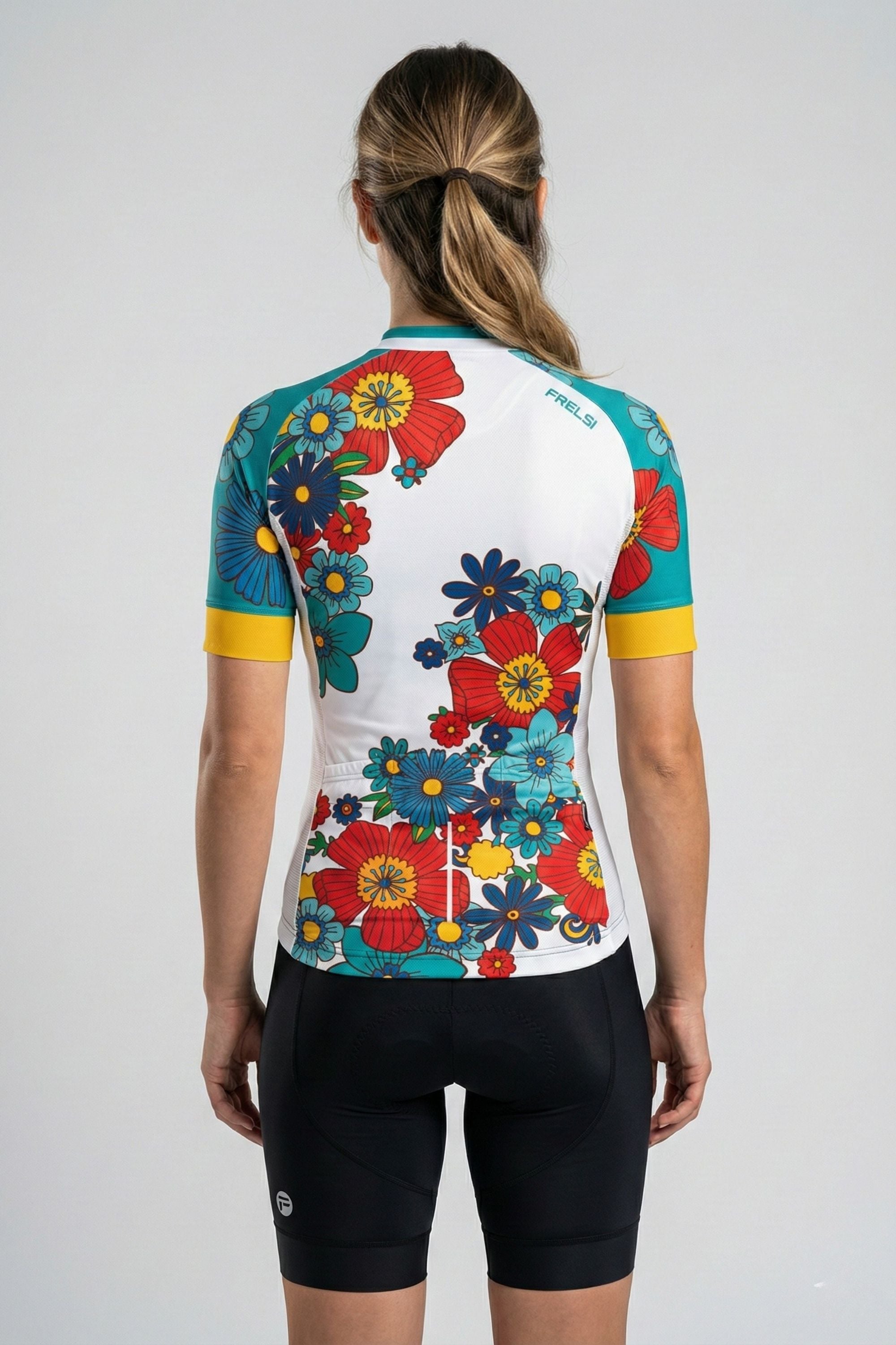 Person wearing a cycling jersey with colorful flowers accents by Cycling Frelsi on a gray background
