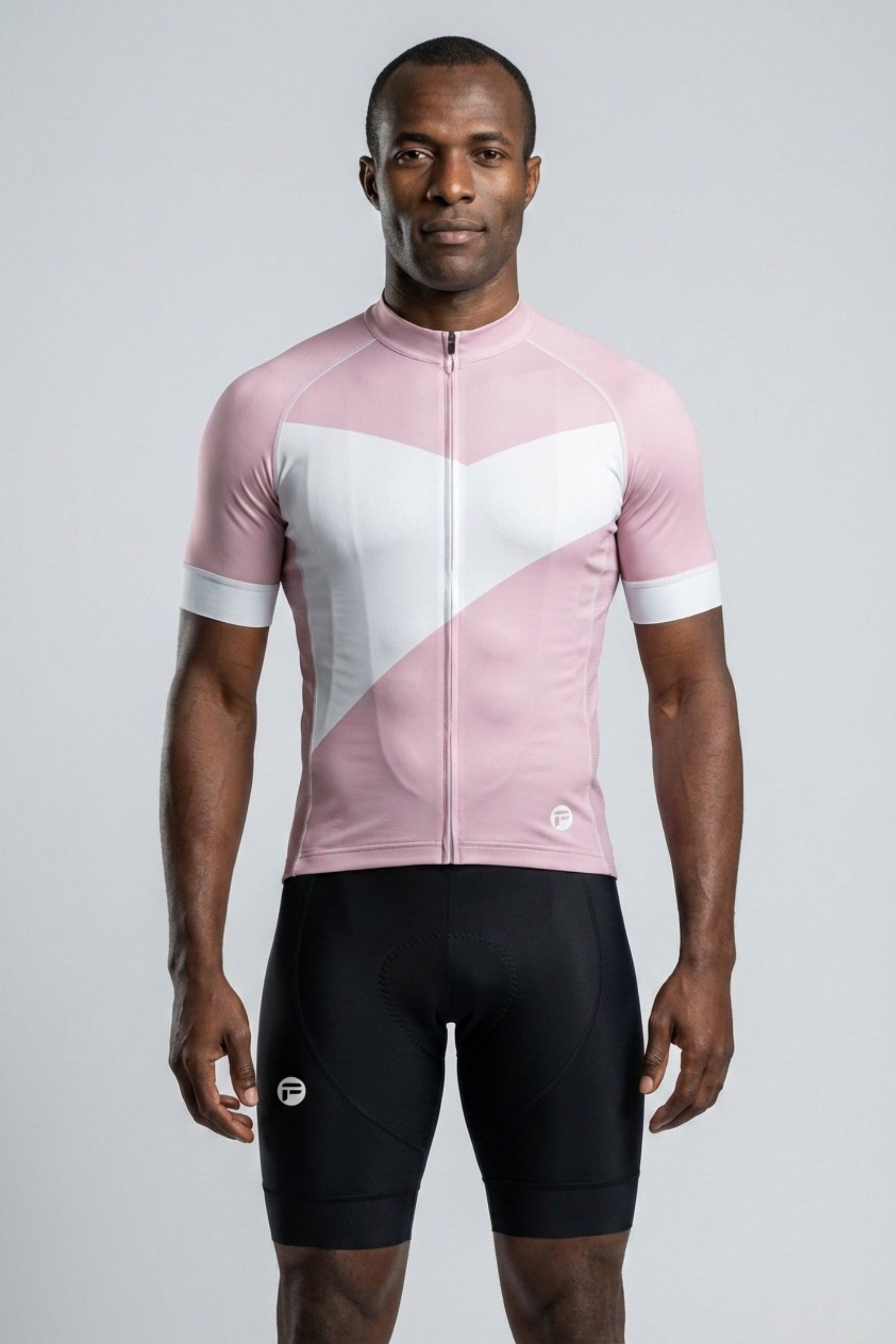 Person wearing a pink and white cycling jersey with black shorts on a gray background
