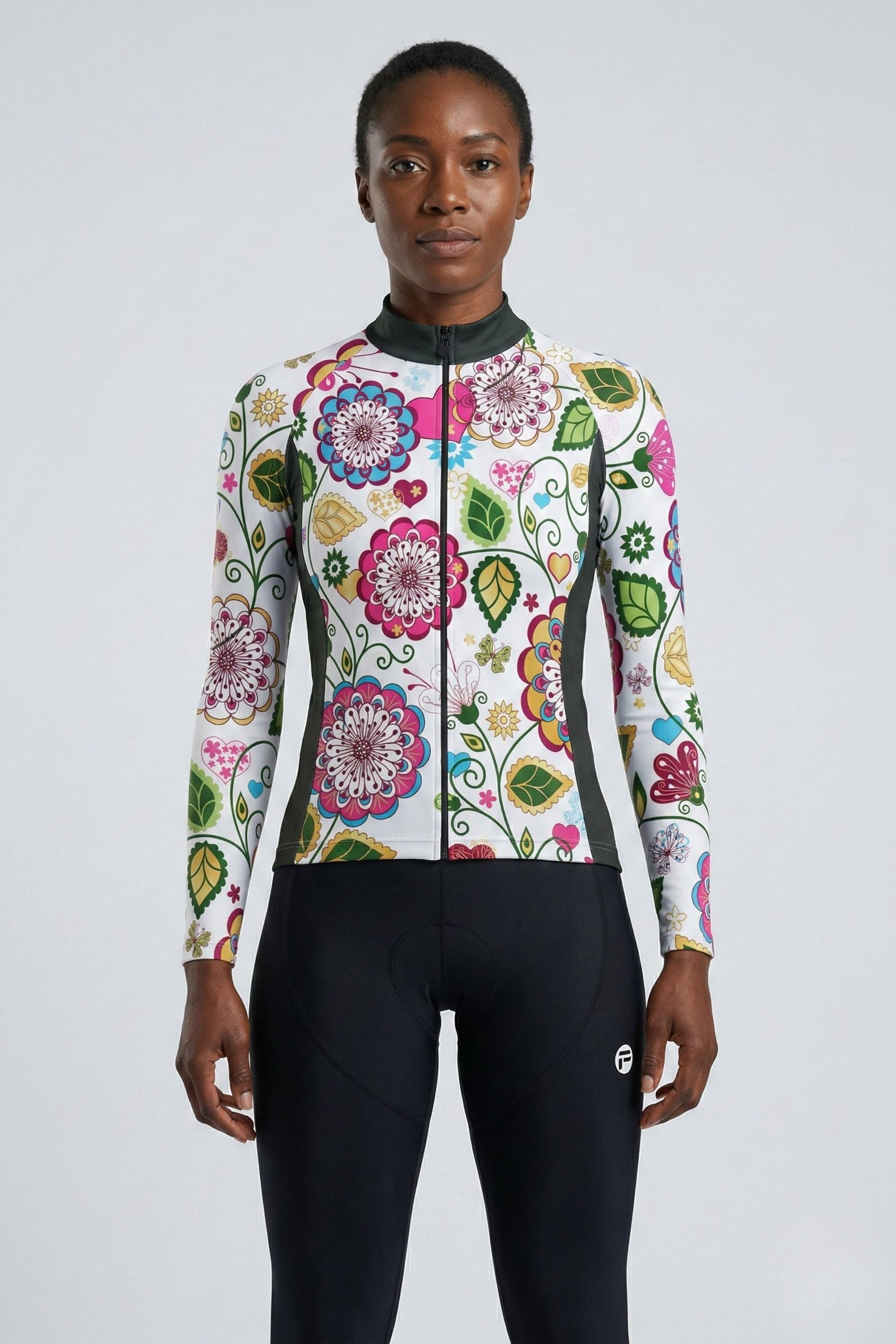 Person wearing a colorful floral cycling jersey and black pants on a light gray background