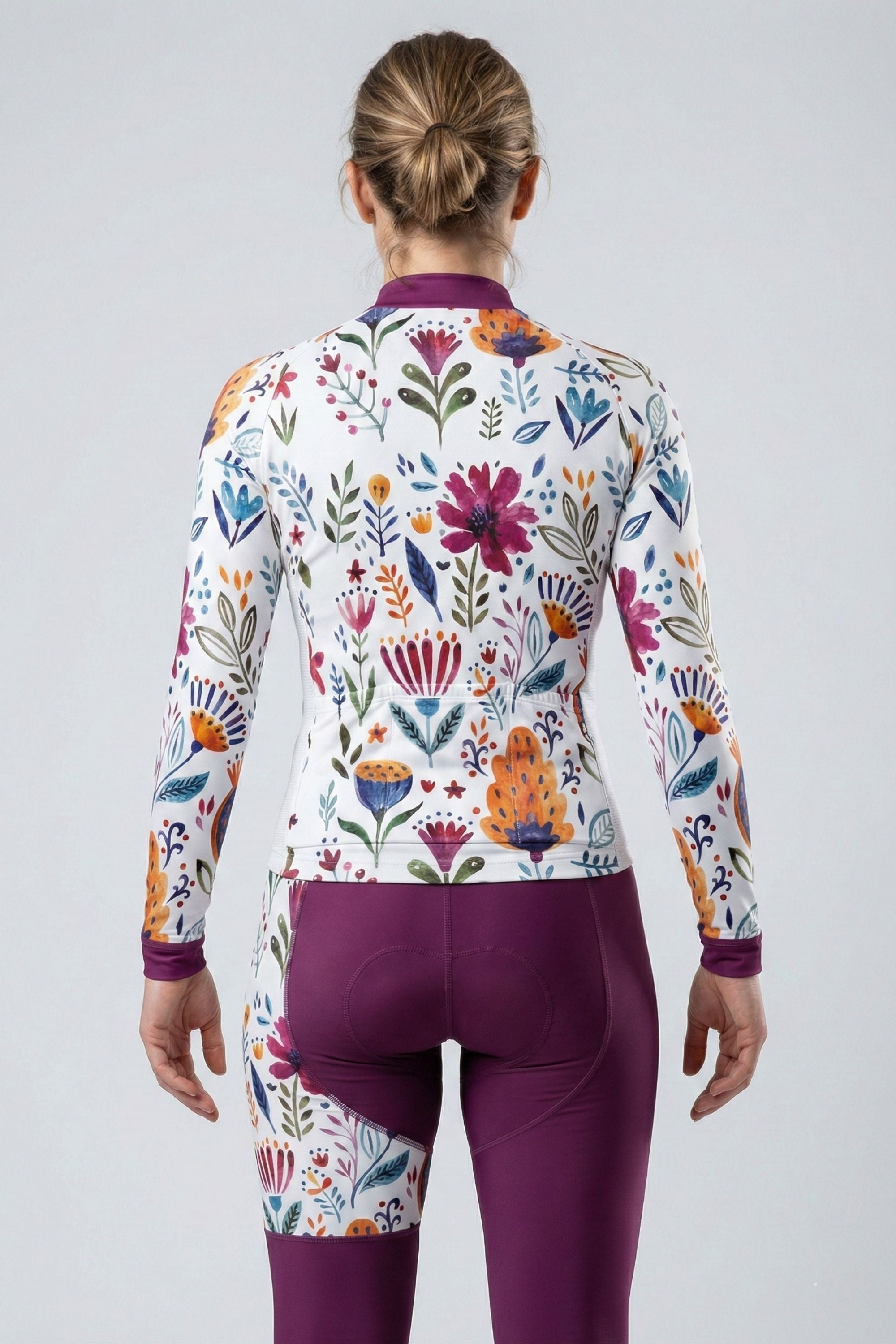 Person wearing a white cycling set with purple flowers accents by Cycling Frelsi on a gray background