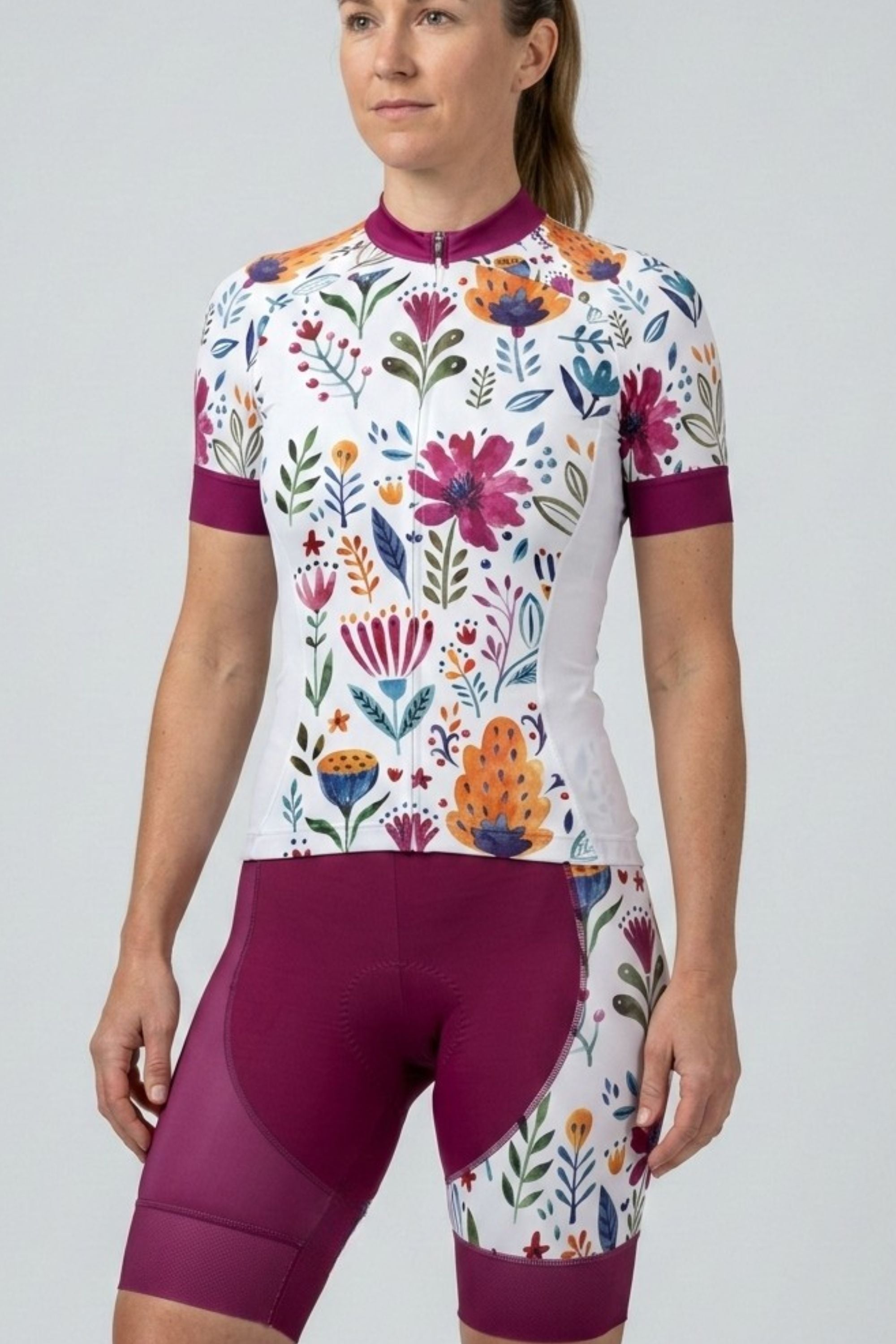 Woman wearing a colorful floral cycling outfit on a plain background