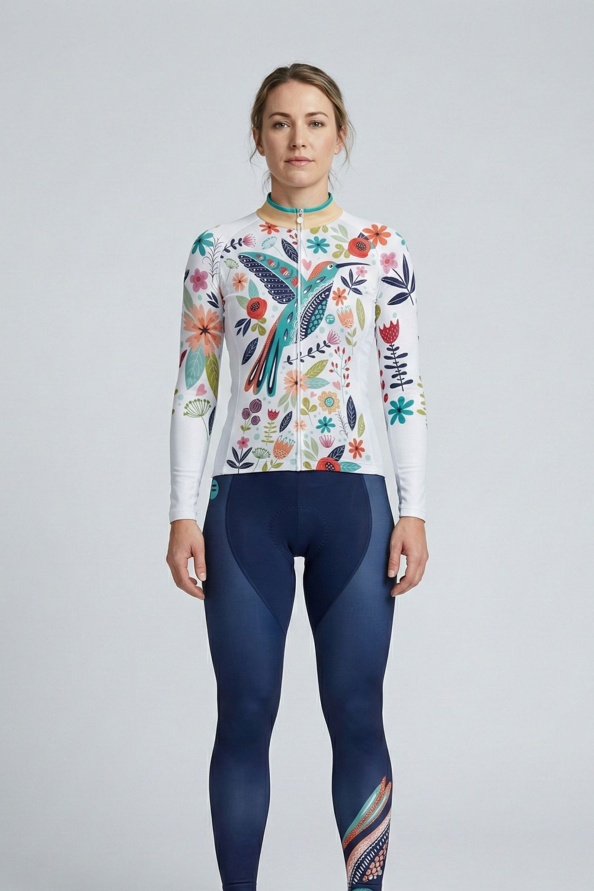 Person wearing a white cycling set with a blue bird and flowers accents by Cycling Frelsi on a gray background