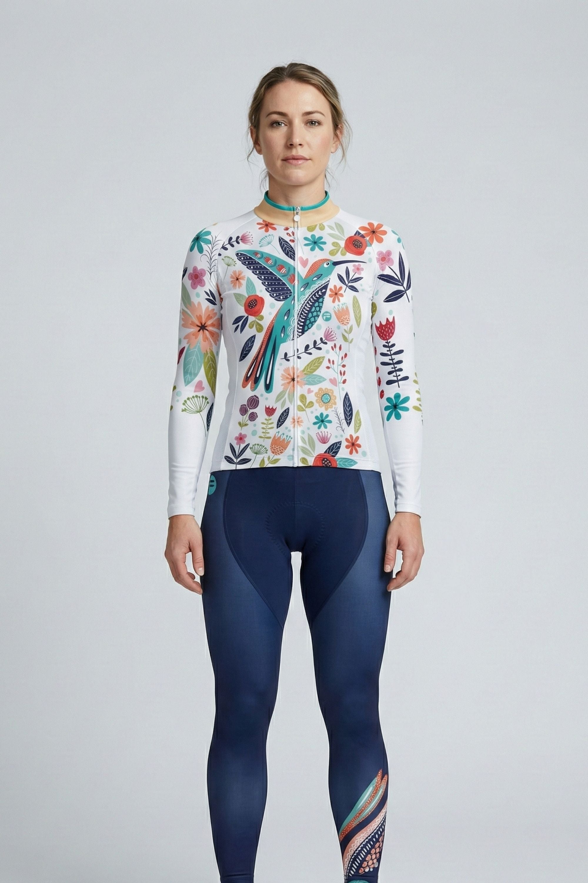 Person wearing a white cycling set with a blue bird and flowers accents by Cycling Frelsi on a gray background