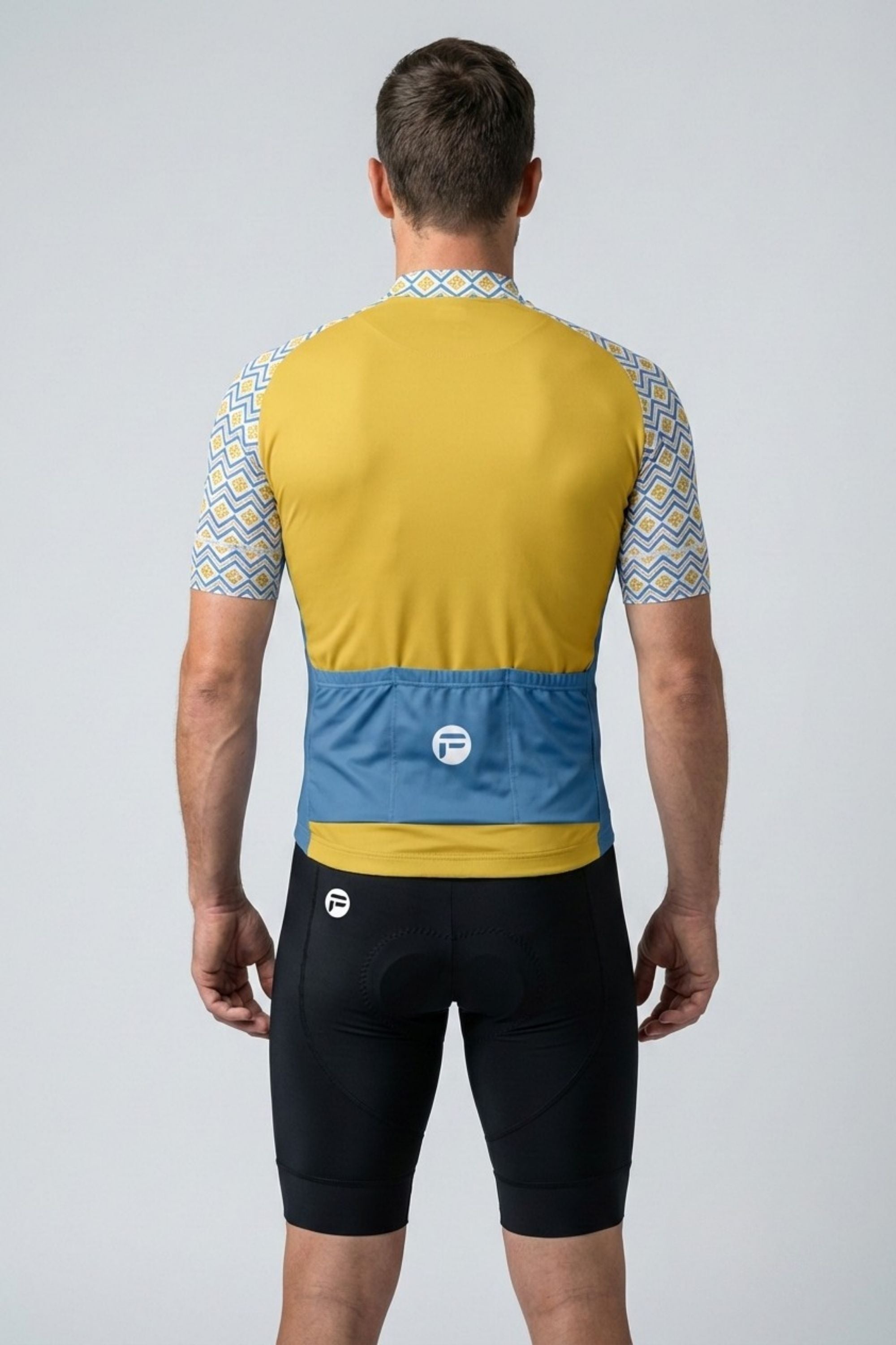 Person wearing a yellow and blue cycling jersey with black shorts on a gray background