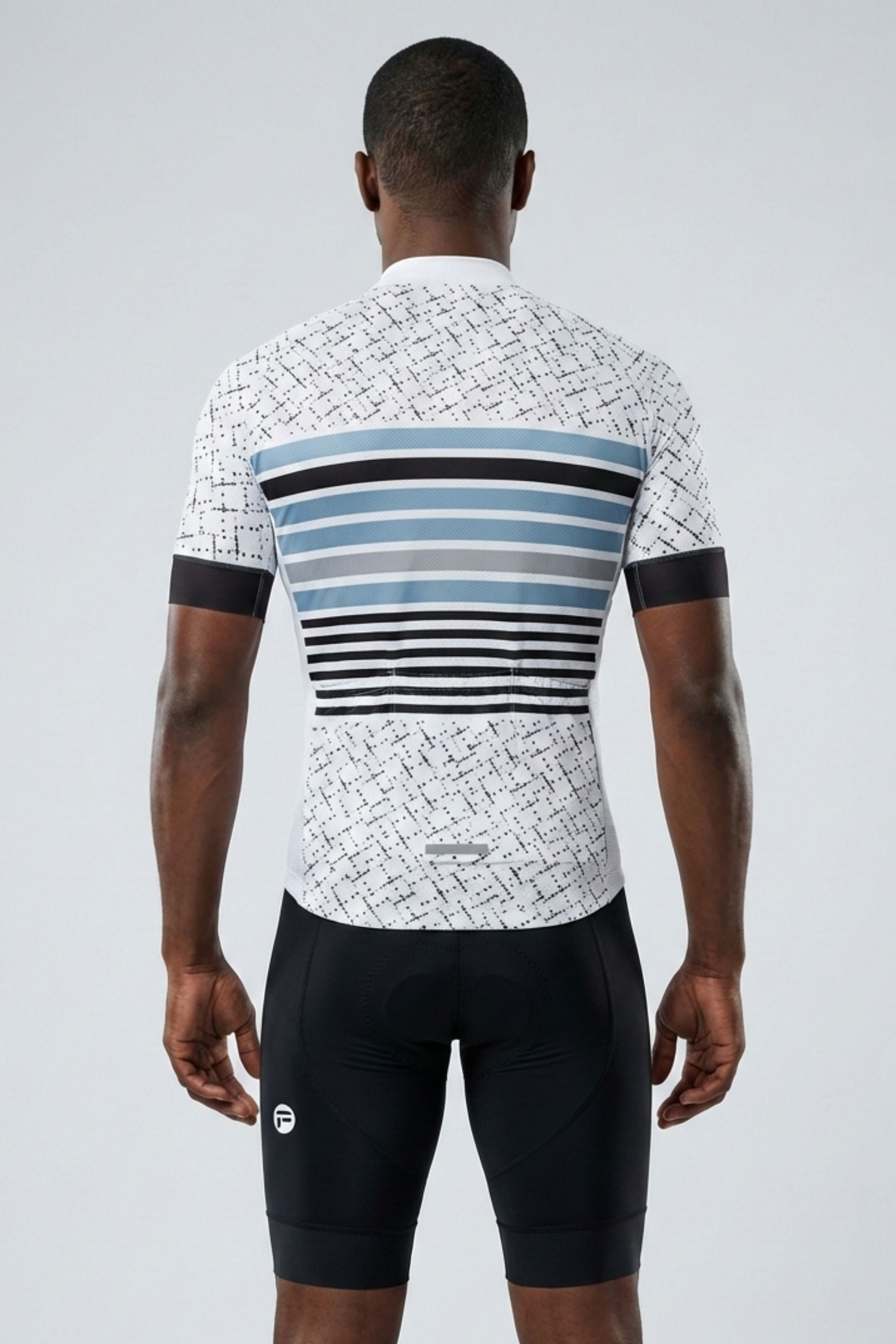 Person wearing a cycling outfit with a patterned jersey and black shorts on a light gray background