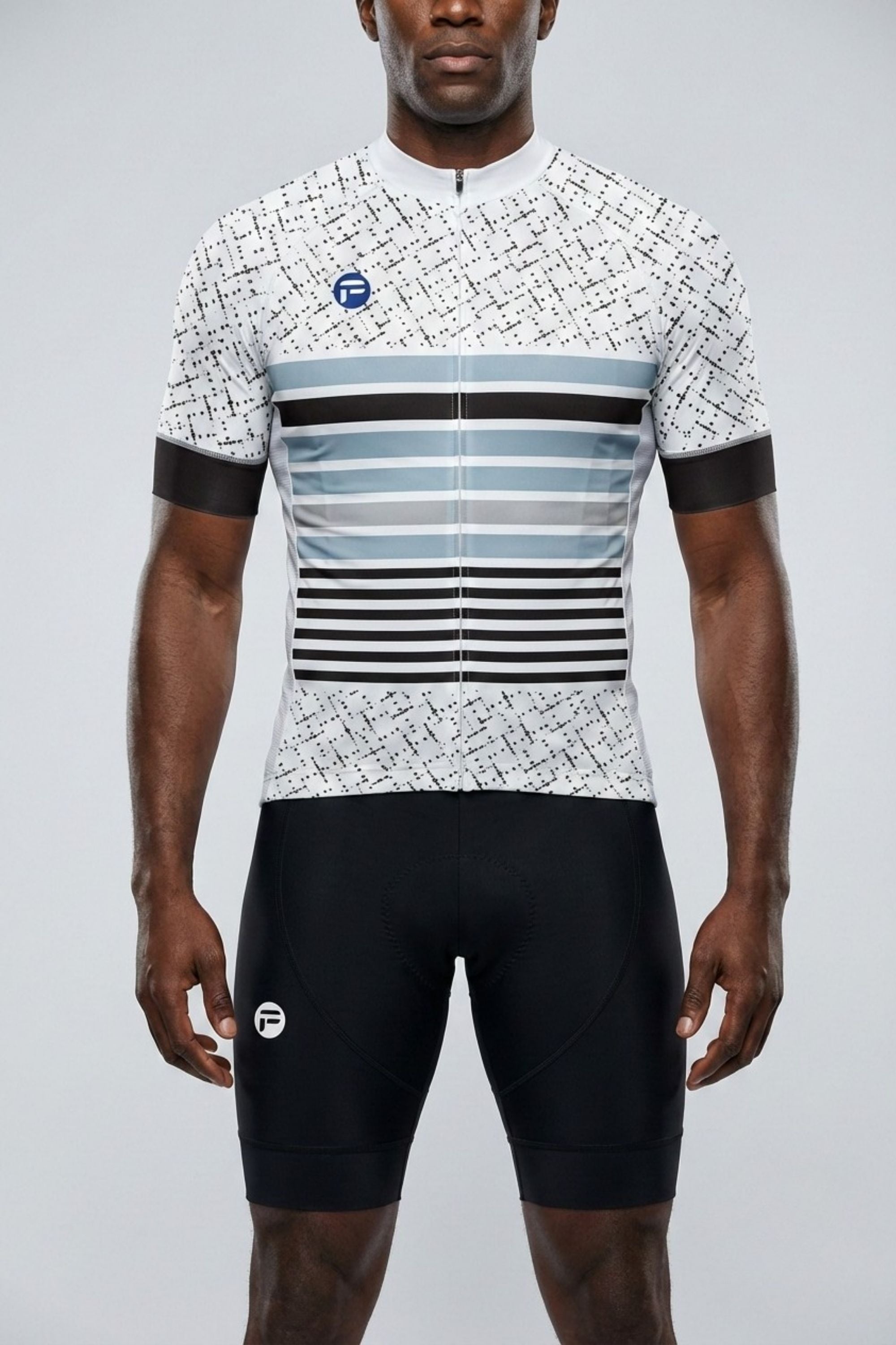 Person wearing a cycling jersey with a geometric pattern and black shorts on a gray background