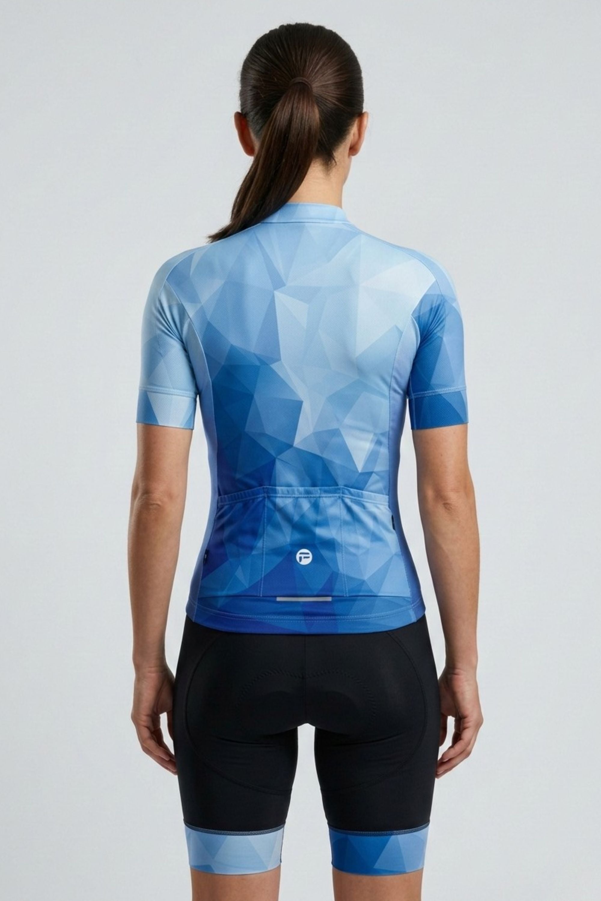 Person wearing a blue geometric patterned cycling jersey and black shorts on a light gray background