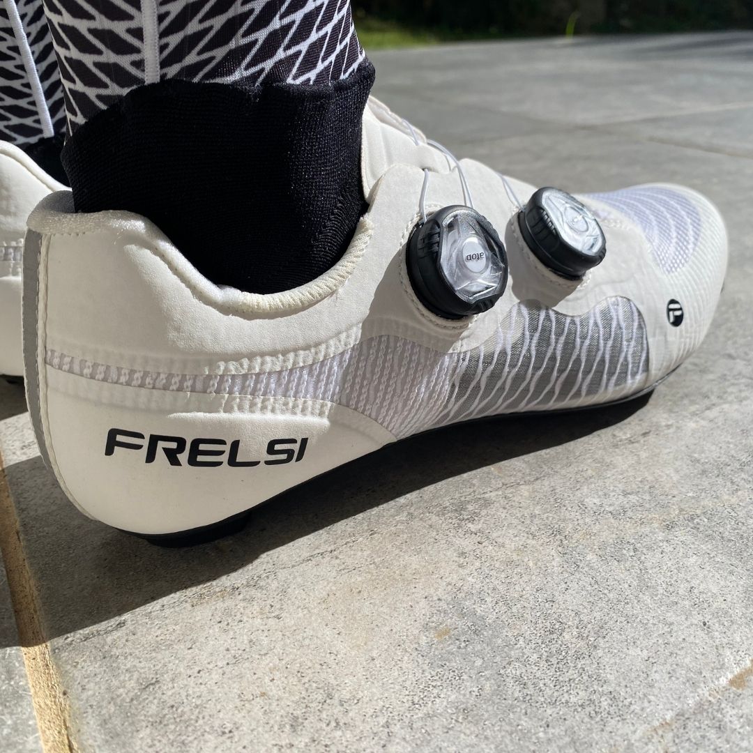 Close-up of Frelsi Pro Carbon Team Shoes: White cycling shoes with a stiff carbon fiber sole and breathable mesh upper, designed for maximum power transfer and comfort.