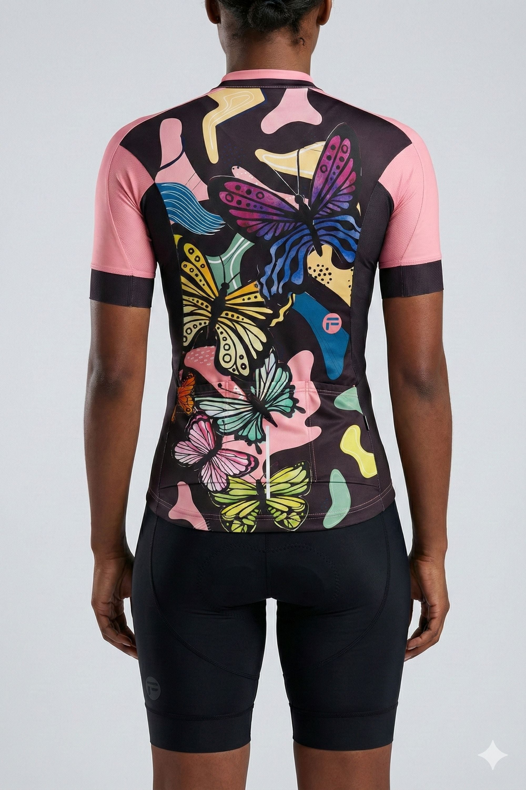 Person wearing a black and pink cycling outfit with butterflies on a plain background by Cycling Frelsi