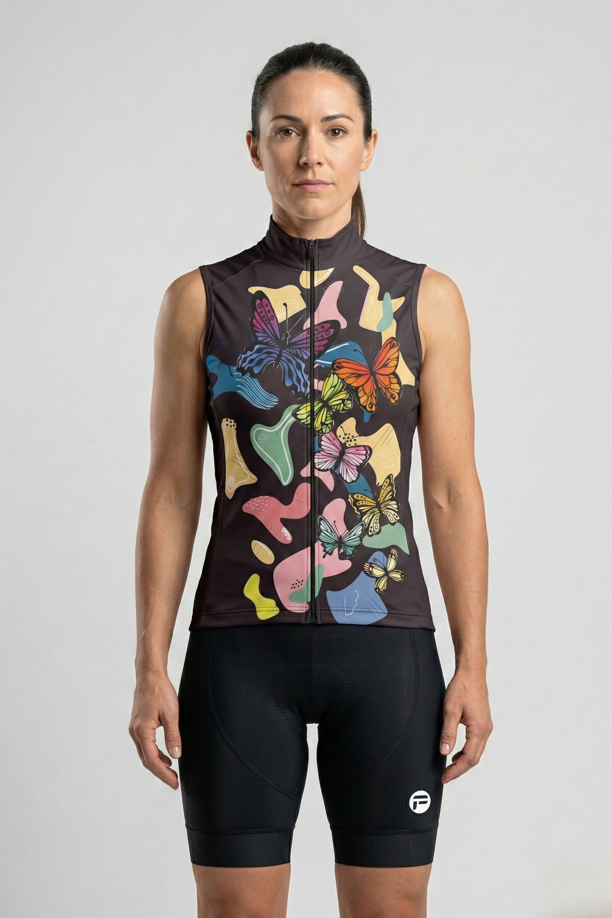 Woman wearing a sleeveless top with butterfly design and black shorts on a light gray background