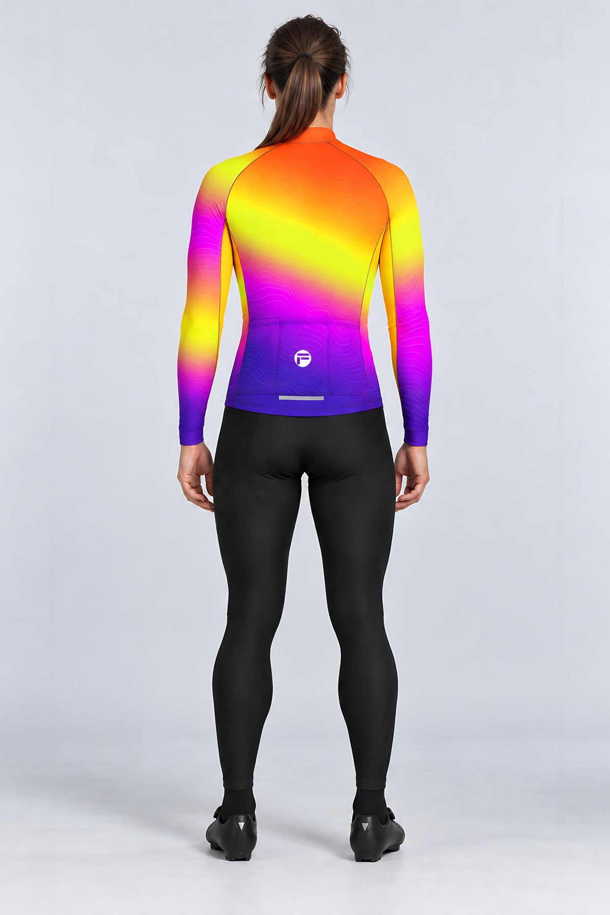 Woman wearing the Sunset Pulse long sleeve cycling jersey with black bib tights - back view