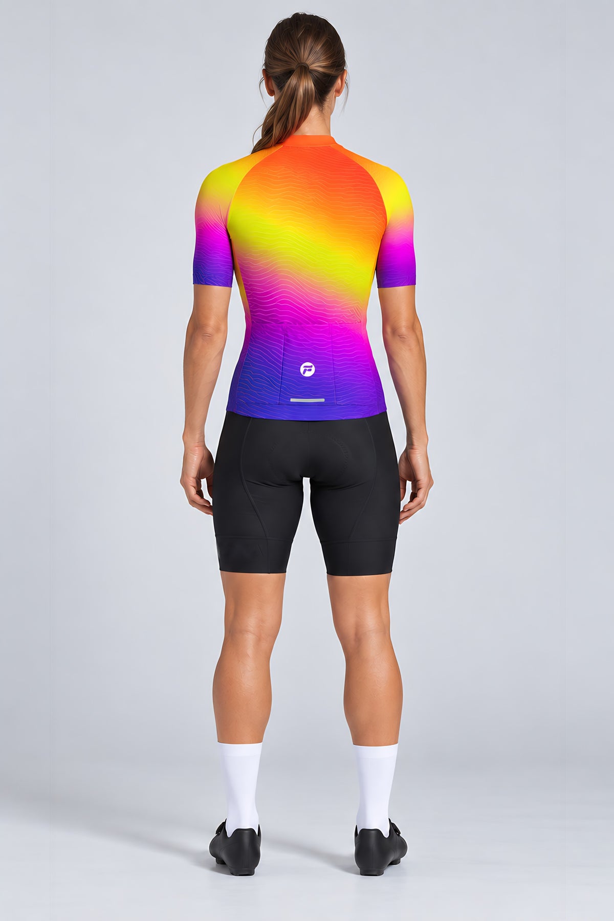 Woman wearing the Sunset Pulse short sleeve cycling jersey with black bib shorts - back view