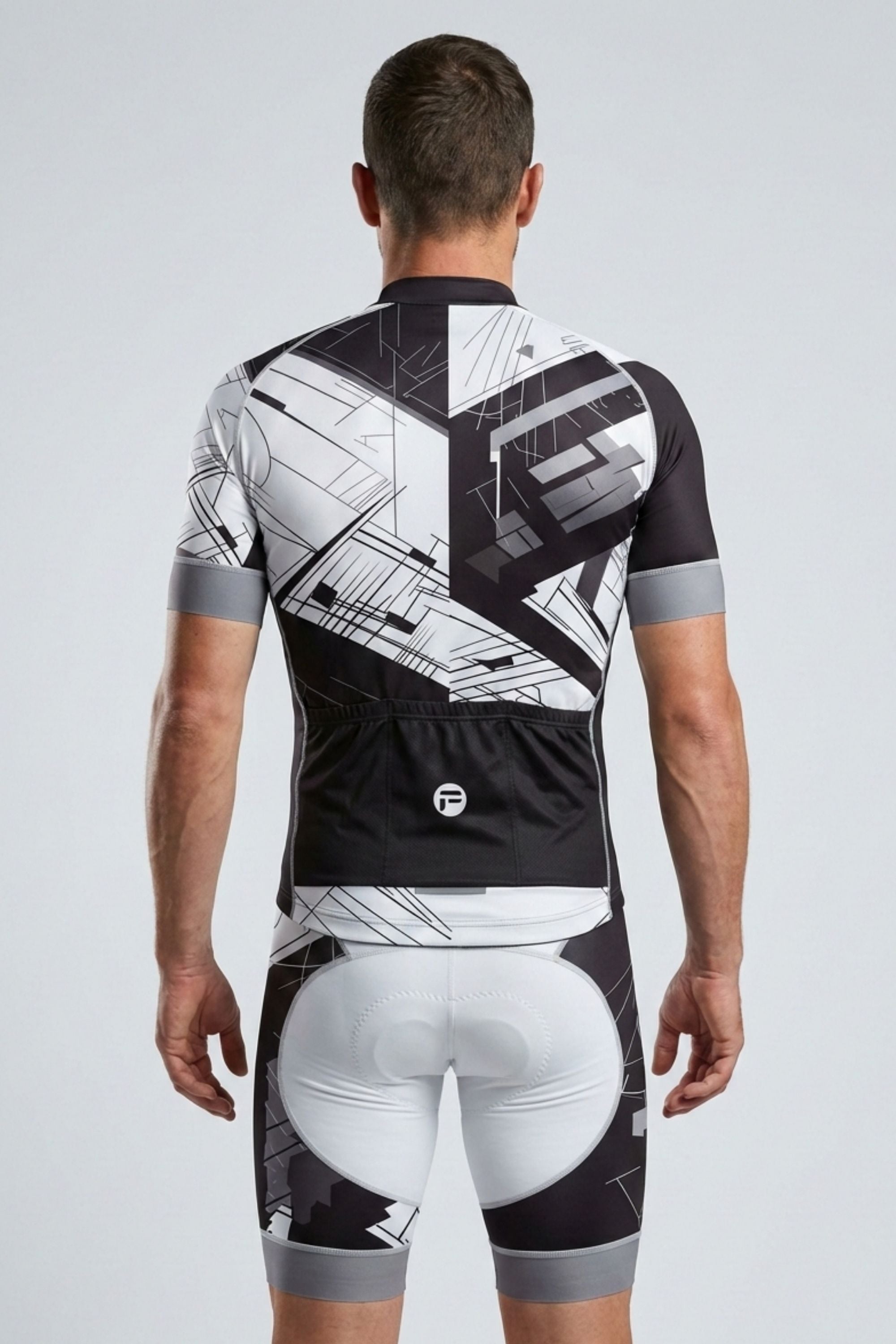 Person wearing a black and white geometric cycling outfit on a light gray background