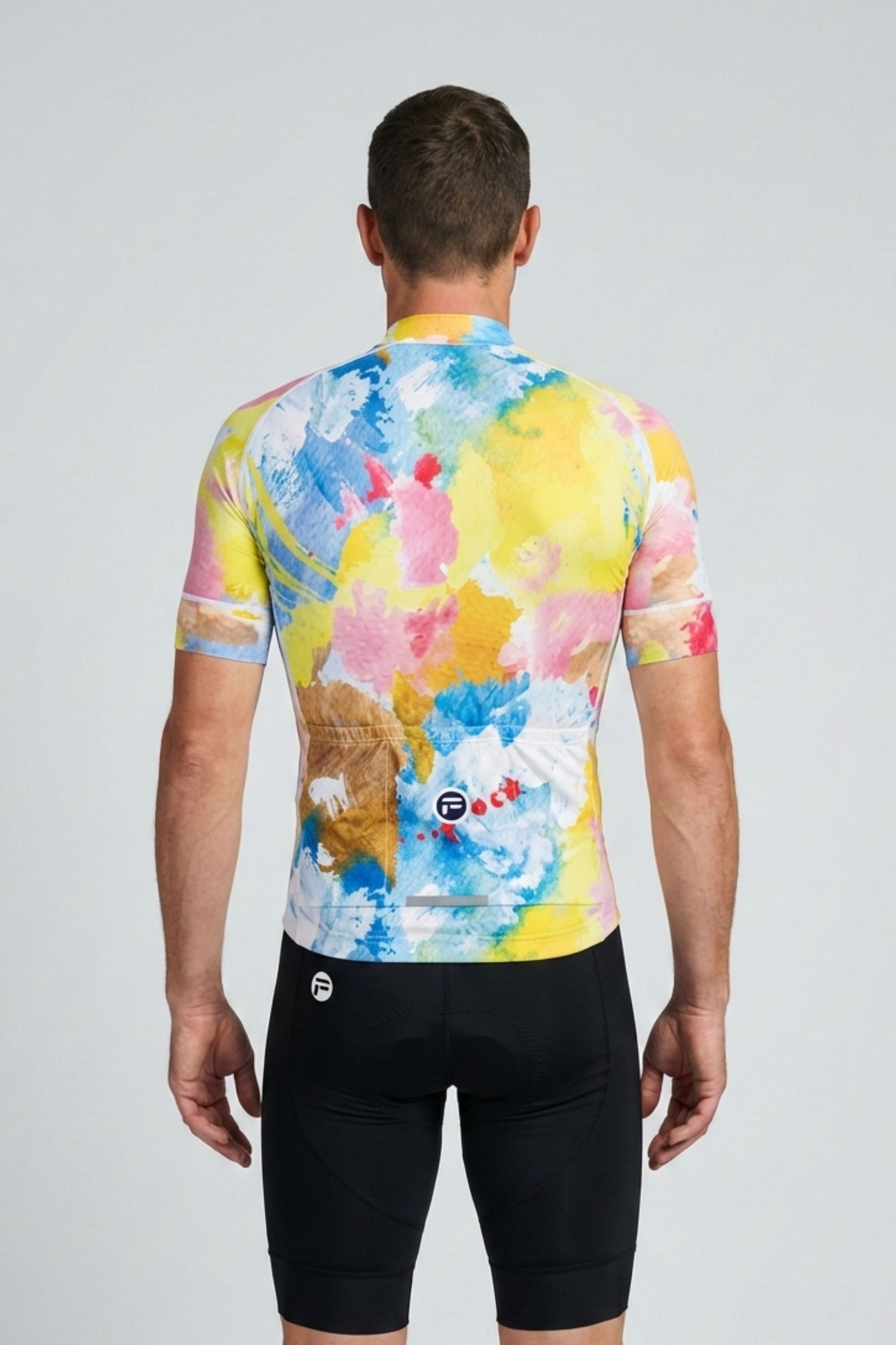 Person wearing a colorful cycling jersey and black shorts on a light gray background