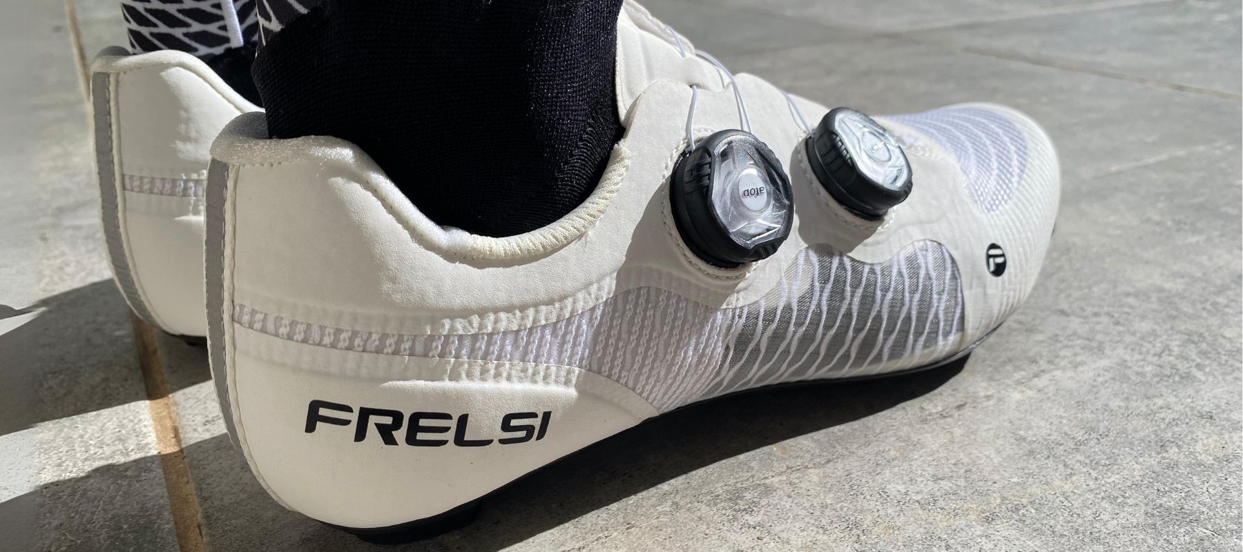 Close-up of Frelsi Pro Carbon Team Shoes: White cycling shoes with a stiff carbon fiber sole and breathable mesh upper, designed for maximum power transfer and comfort.