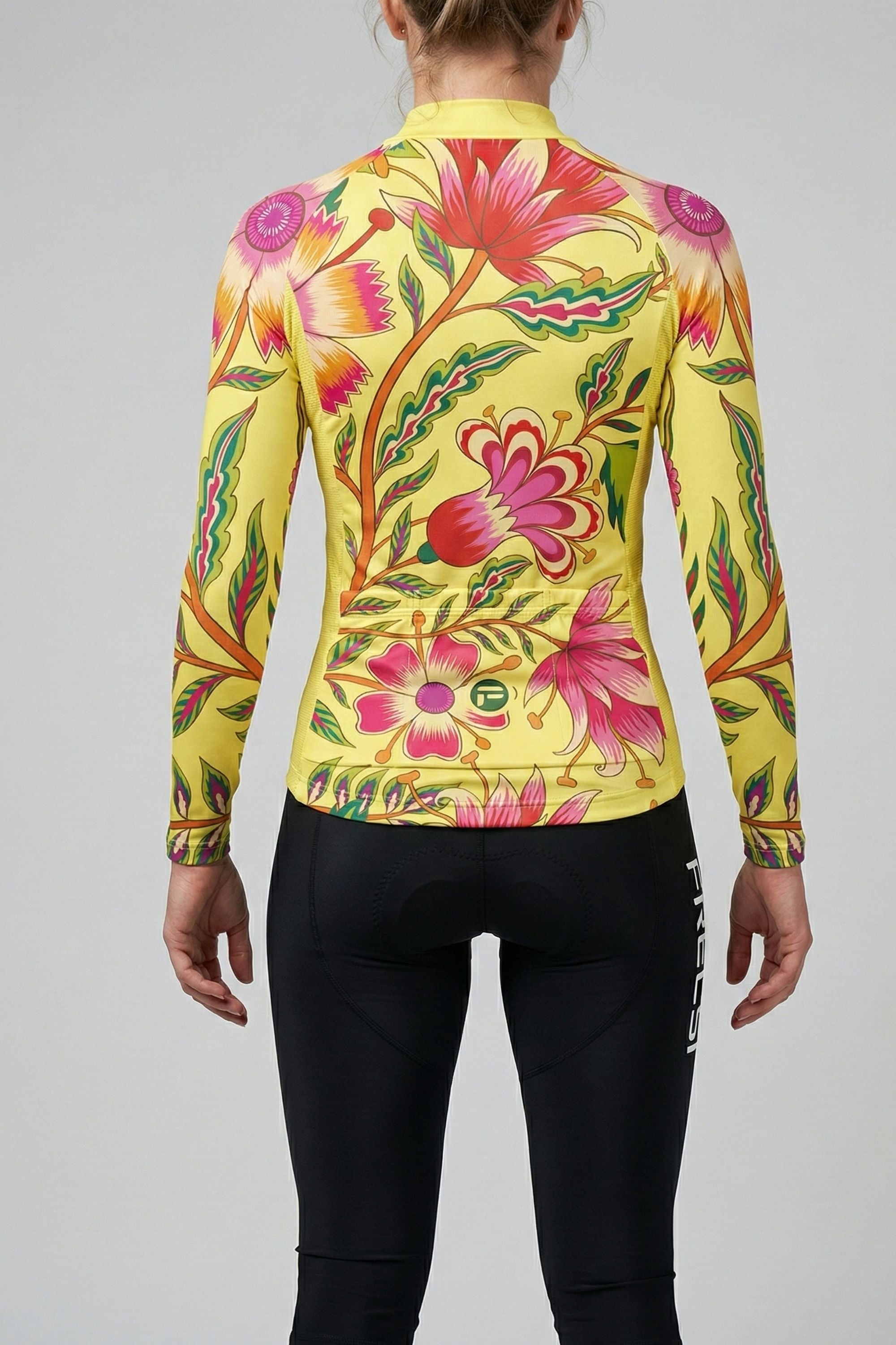 Person wearing a yellow cycling jersey with pink flower accents by Cycling Frelsi on a gray background