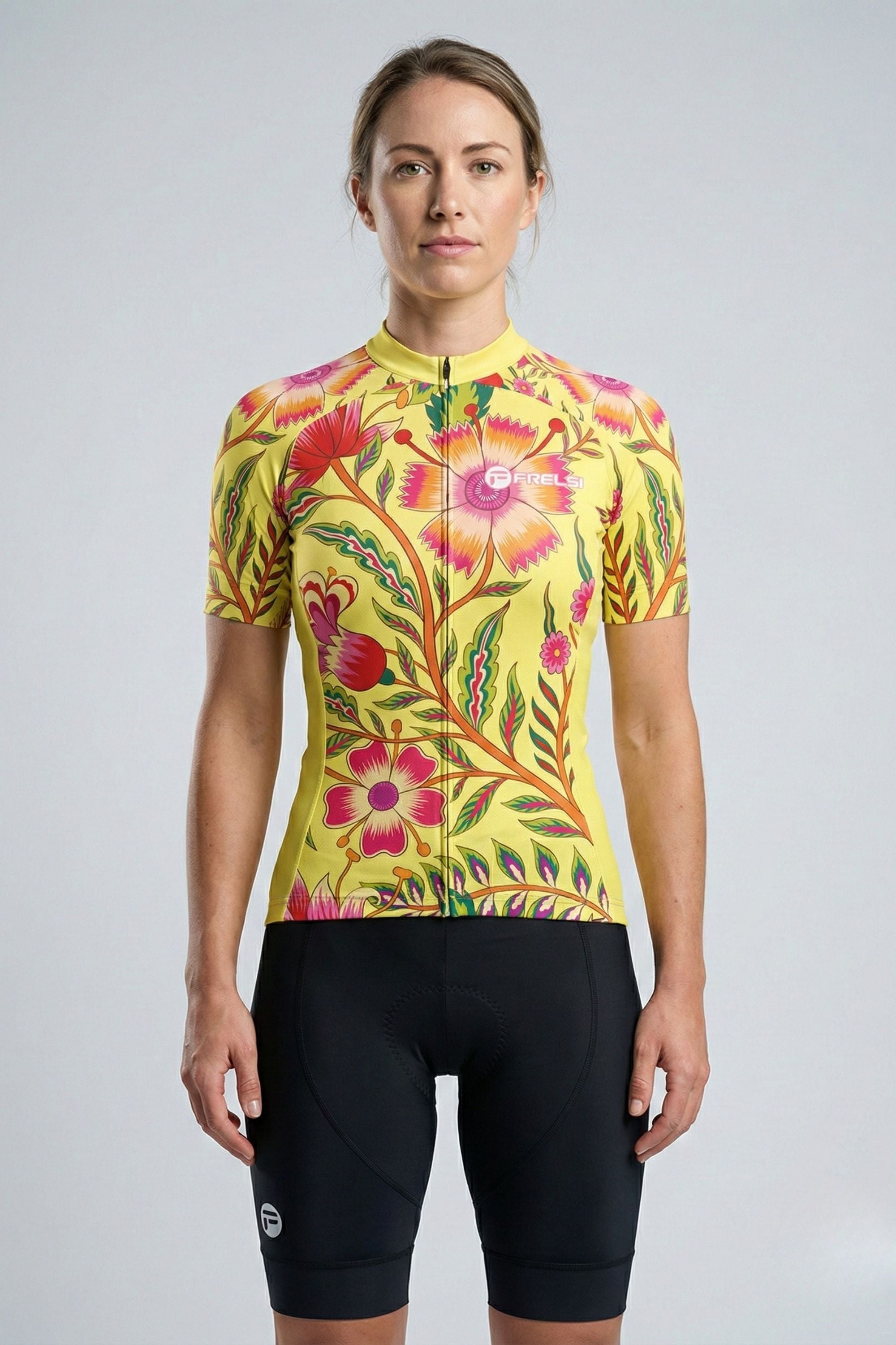 Person wearing a yellow cycling jersey with pink flowers accents by Cycling Frelsi on a gray background