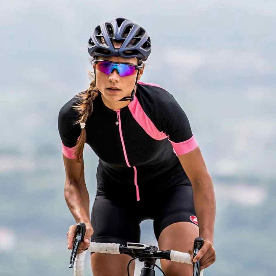 A Women wearing a black and pink Cycling Frelsi jersey while riding on her road bicycles
